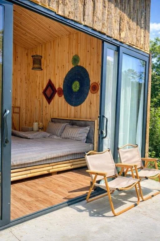 Bed photographed through the window of a wooden, a-frame cottage at Sapa Retreat Homestay.