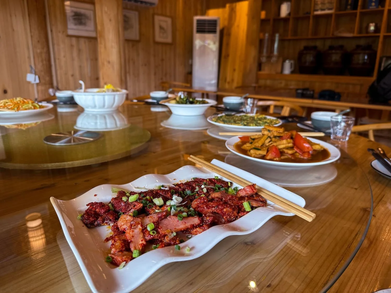 Several local dishes are served on a round dining table in a traditional restaurant. Meal choices on a group tour China may be limited, making it harder to control your food budget and dining preferences.