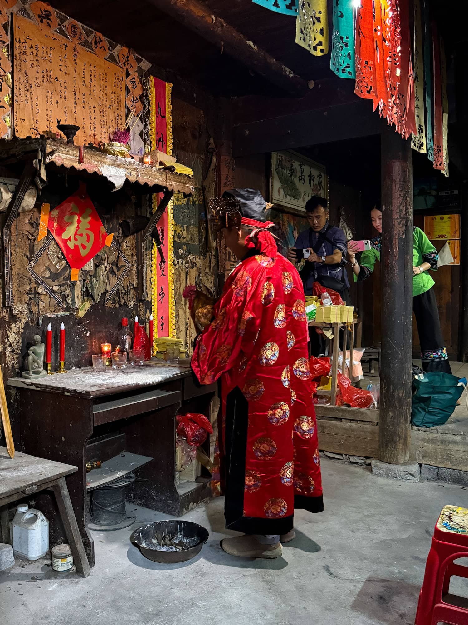 Miao shaman performing a traditional ritual inside a village home. This 2 week China itinerary includes unique cultural experiences.