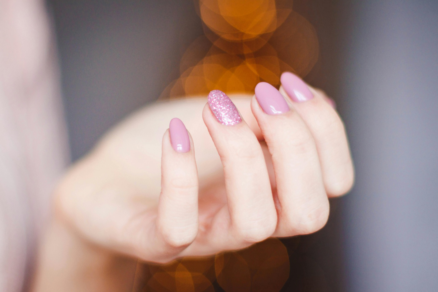 A cropped picture of a woman with pink nail art