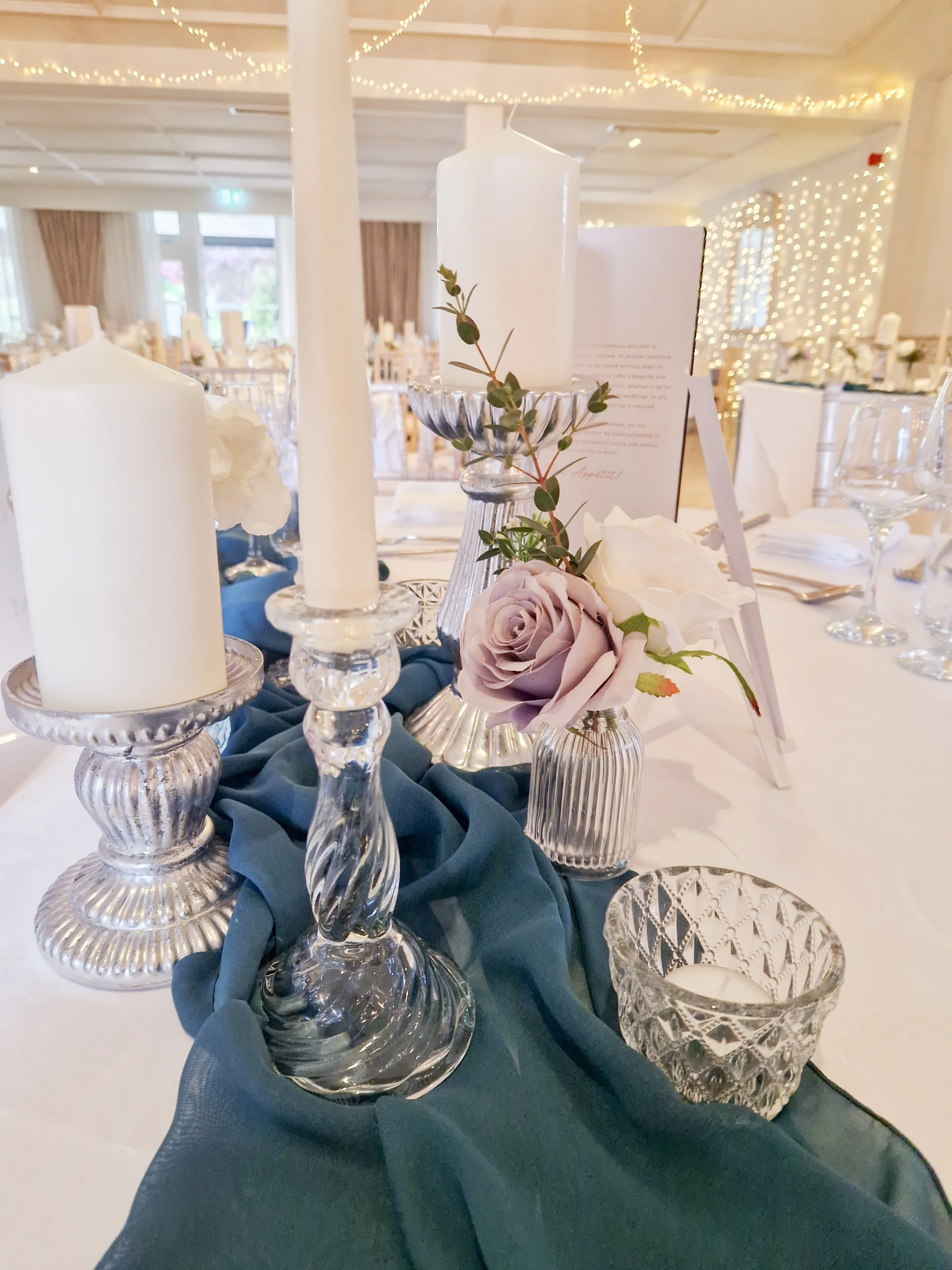 Silver Mercury Centrepiece with ivory taper candles in cut glass candlesticks bud bud vases and tealights on a chiffon table runner