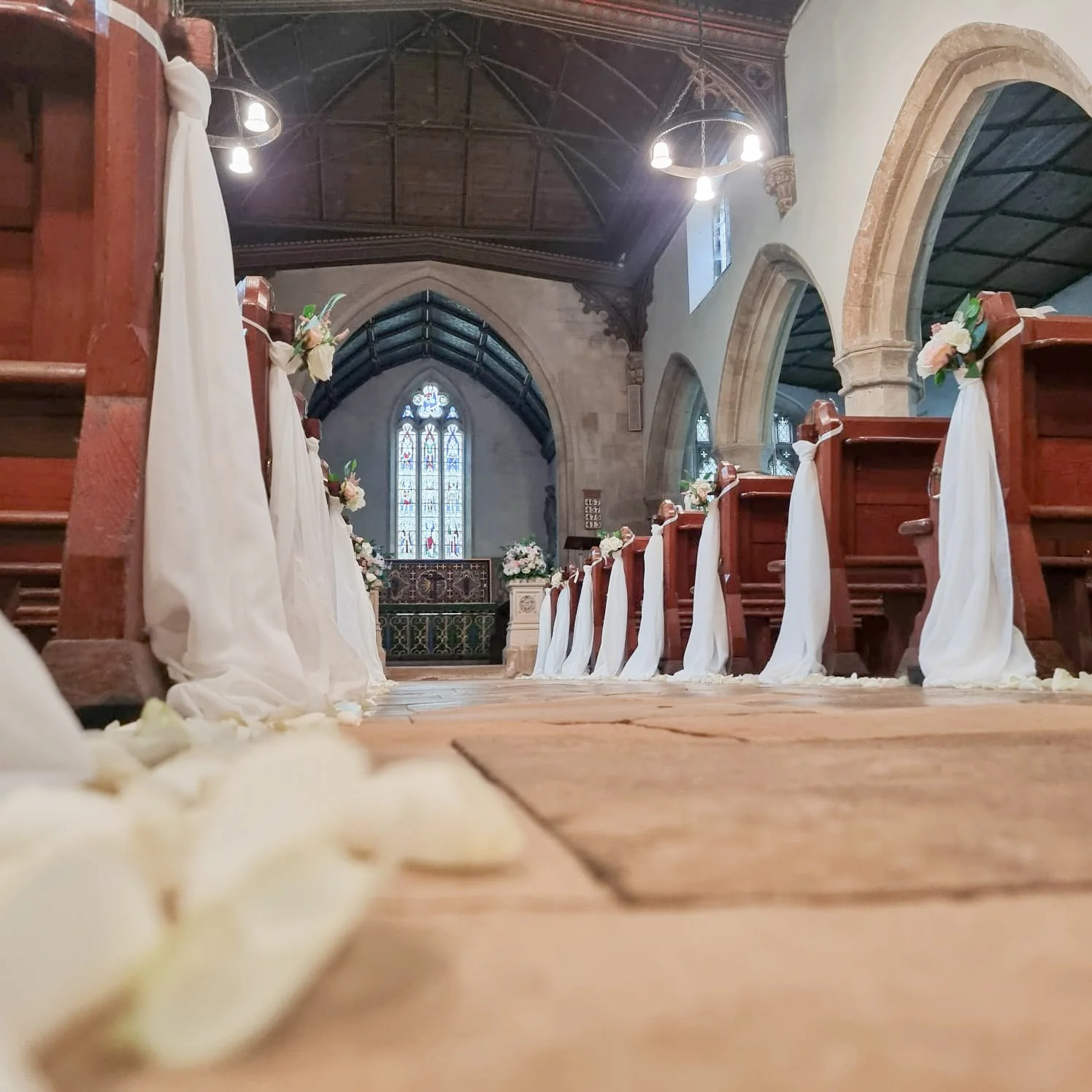 pew ends styled with ivory drapes at st Bartholomew's church Gloucestershire