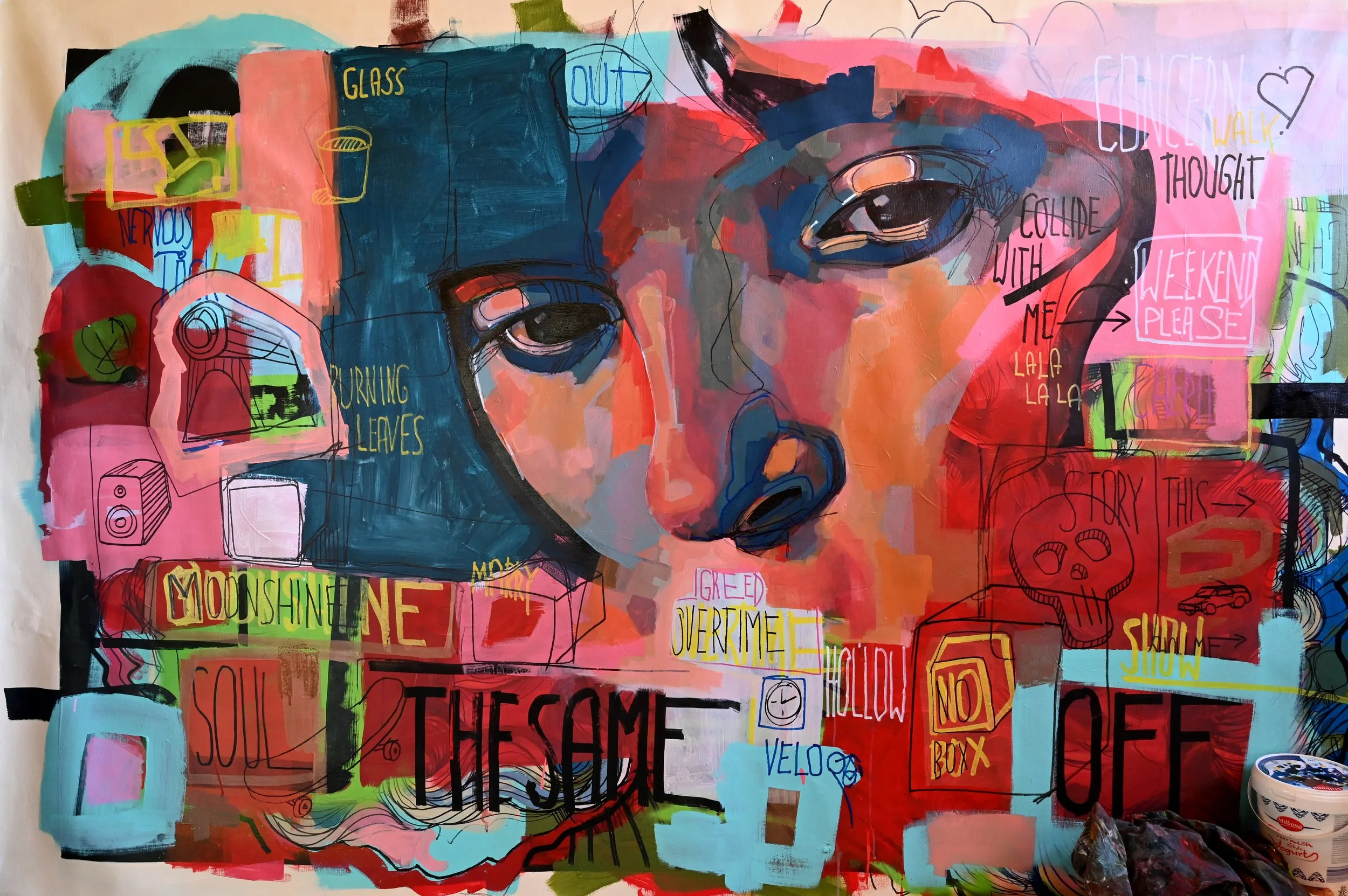 Colorful abstract mural of a woman with expressive eyes and lips, featuring various words and doodles, including 'THE SAME' and 'OFF', with neon colors and mixed media elements.