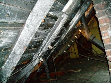 Extensive Fire Damage Compromises Roof Structure Behind Hidden Attic Access in Birmingham Home