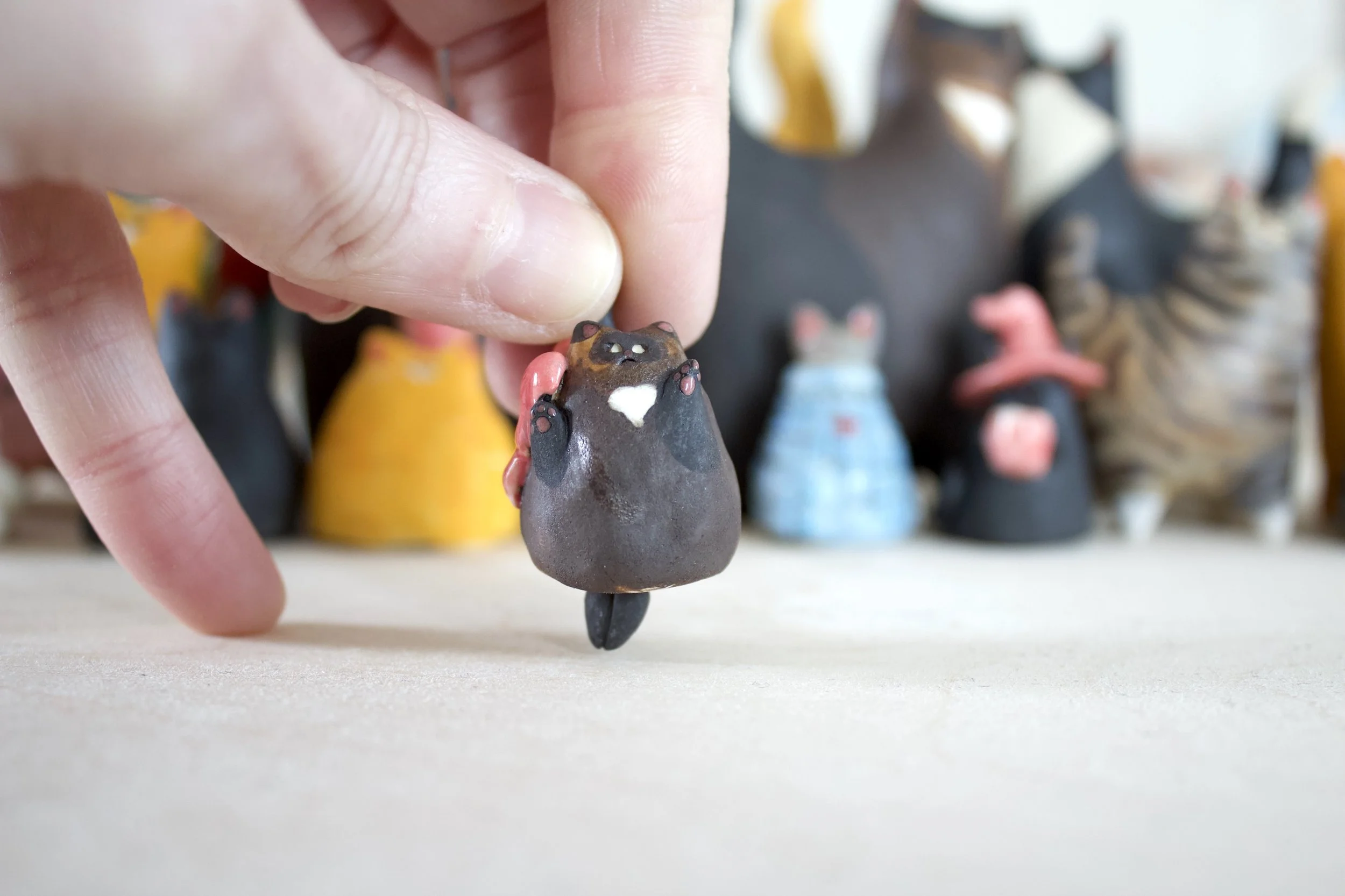 Handmade Chocolate Point Siamese ceramic cat chime shown in hand for scale.jpeg