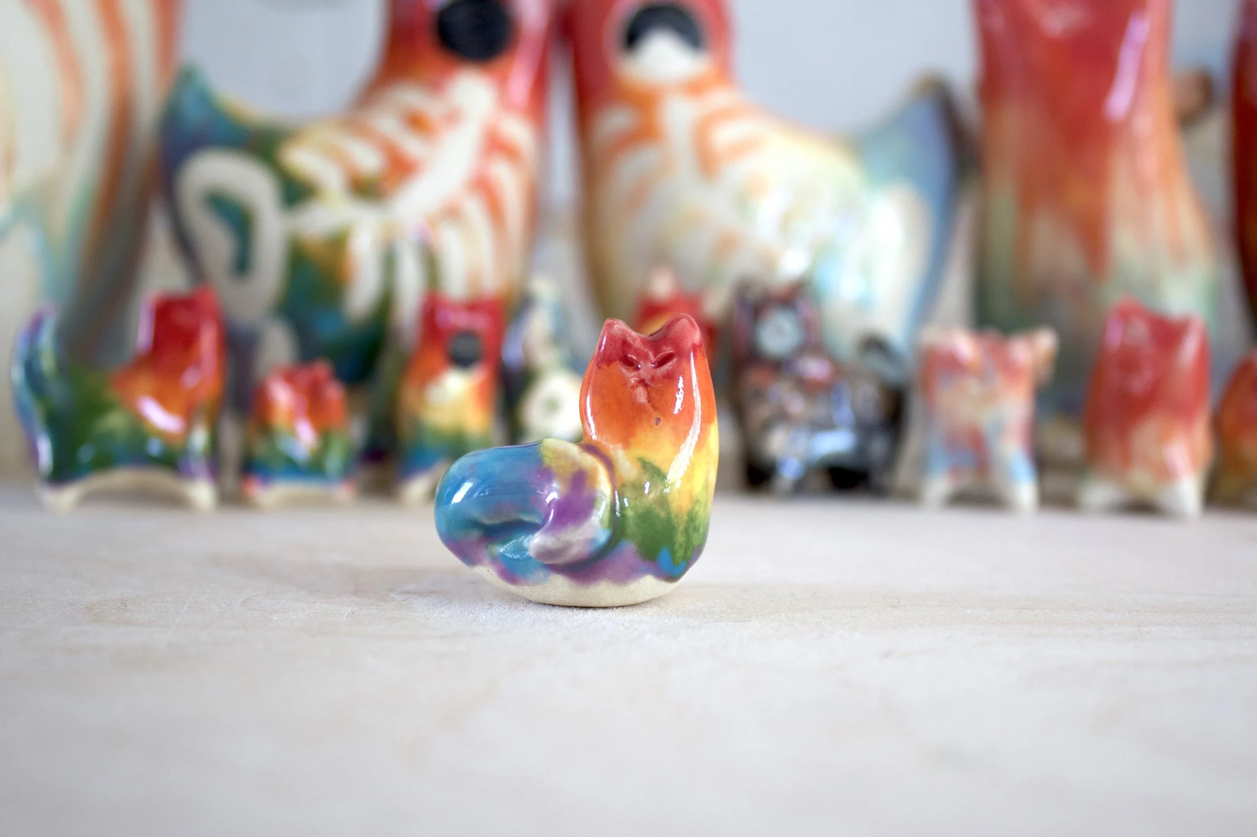 One-of-a-kind handmade ceramic rainbow snake cat sculpture viewed from the front.