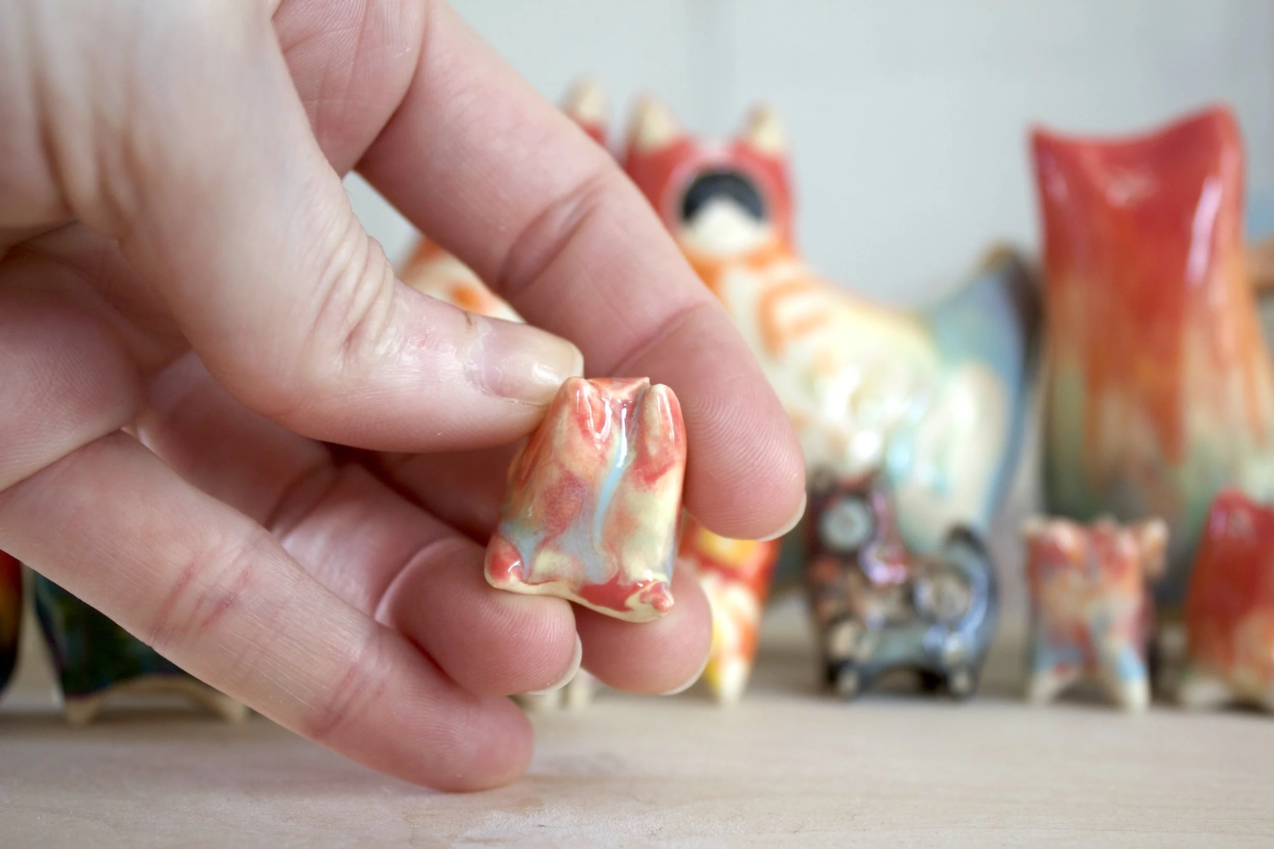 Handmade ceramic Pastel Rainbow Cat No. 1 shown in hand to demonstrate size and scale.jpeg