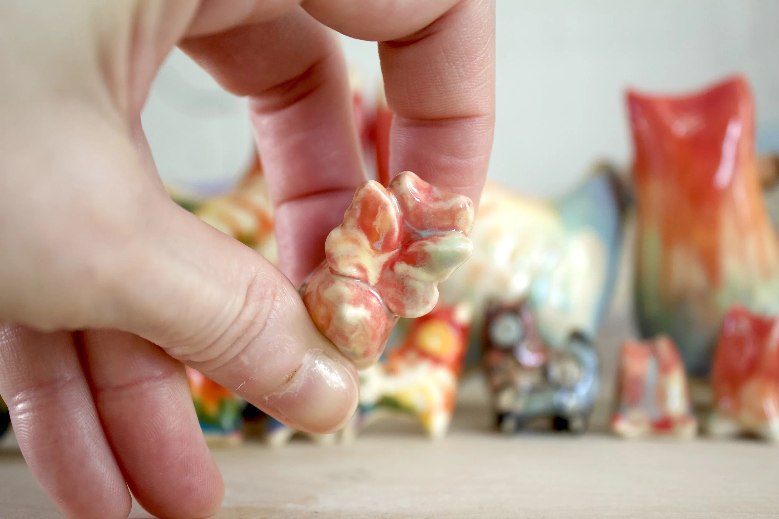 Handmade ceramic Pastel Rainbow Butterfly Cat shown in hand to demonstrate size and scale ad for wing detail.jpeg