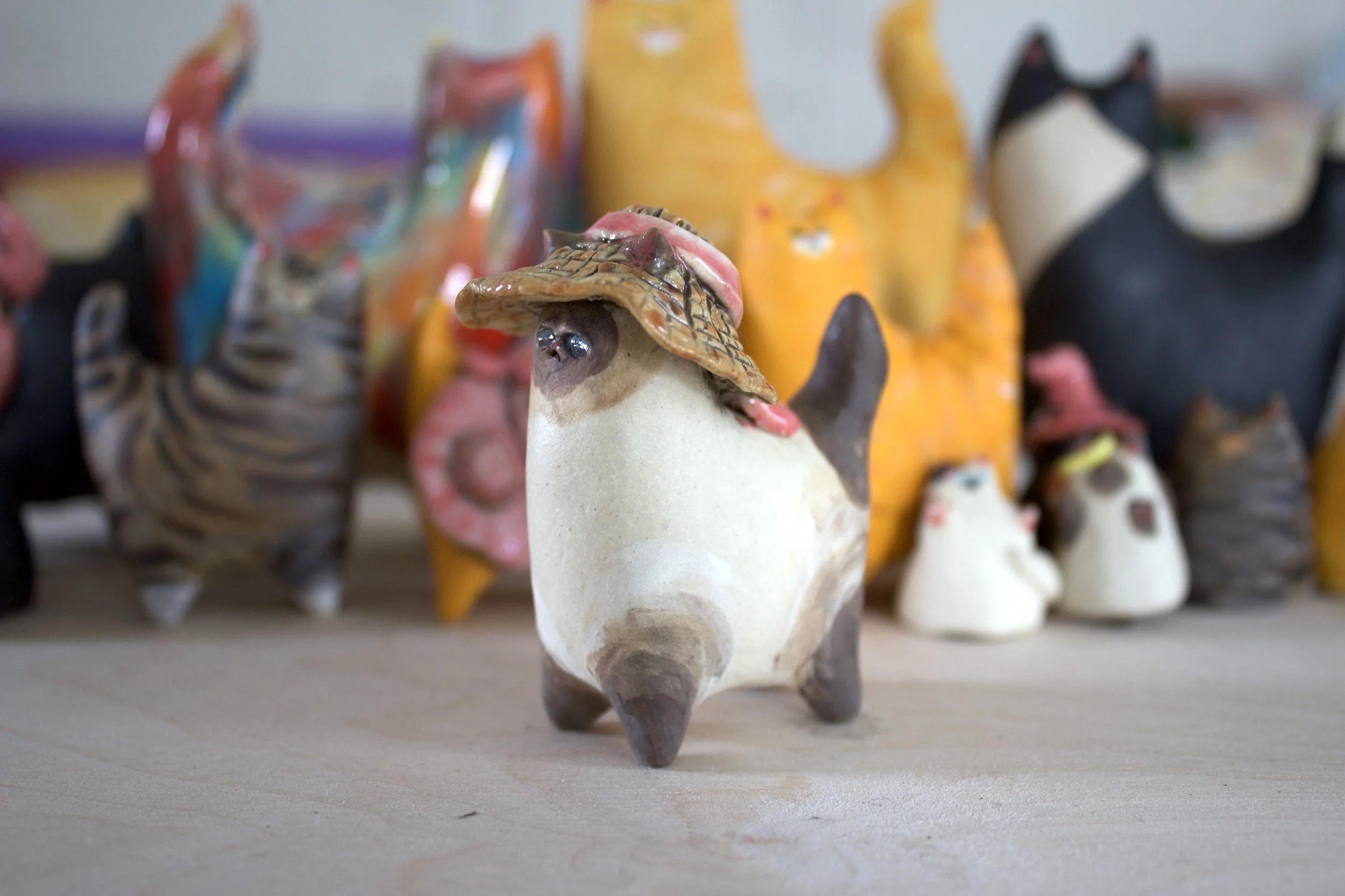 Chocolate Point Siamese handmade ceramic cat sculpture with summer hat and pink bow.jpeg
