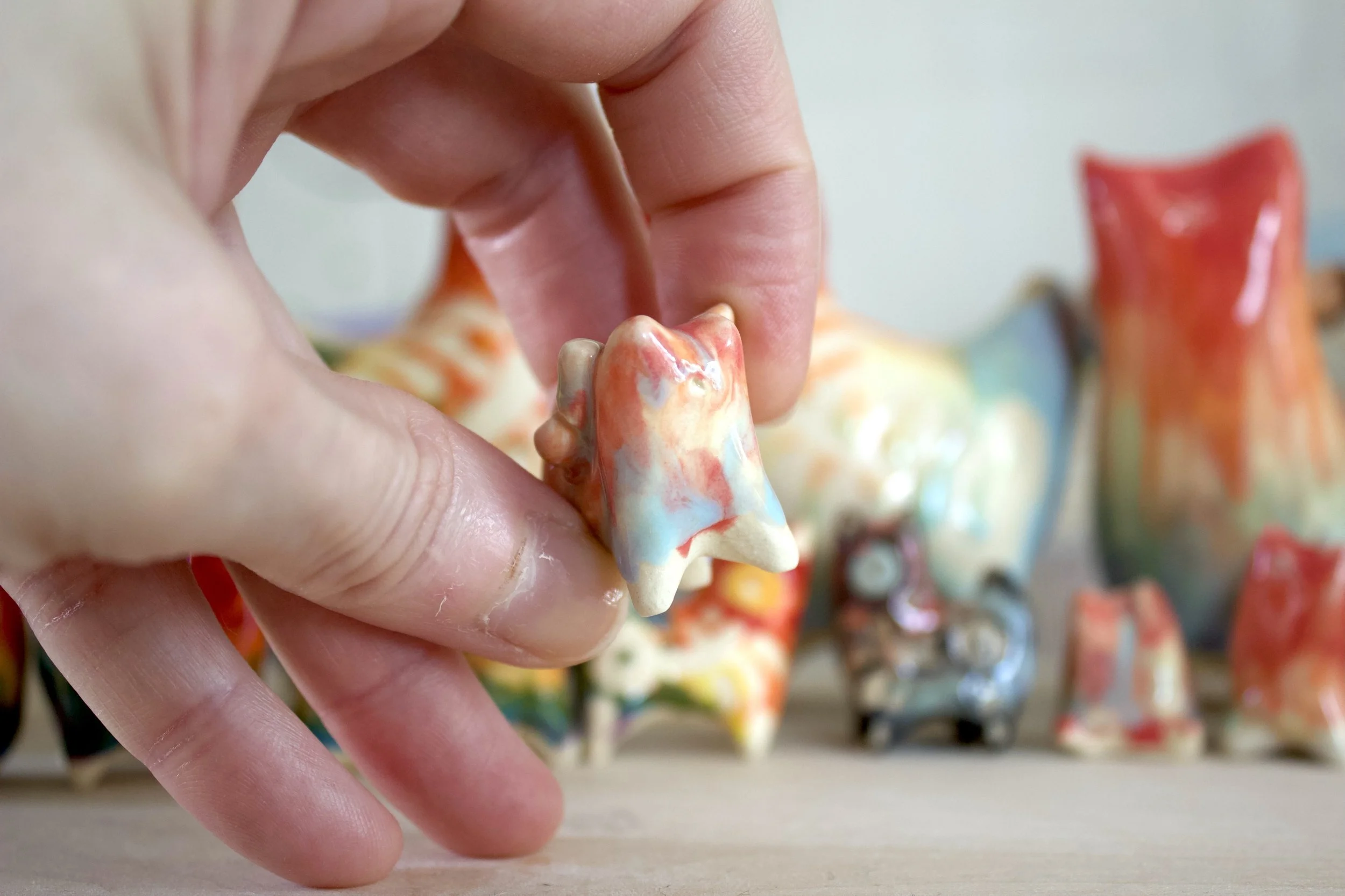 Handmade ceramic Pastel Rainbow Butterfly Cat shown in hand to demonstrate size and scale.jpeg