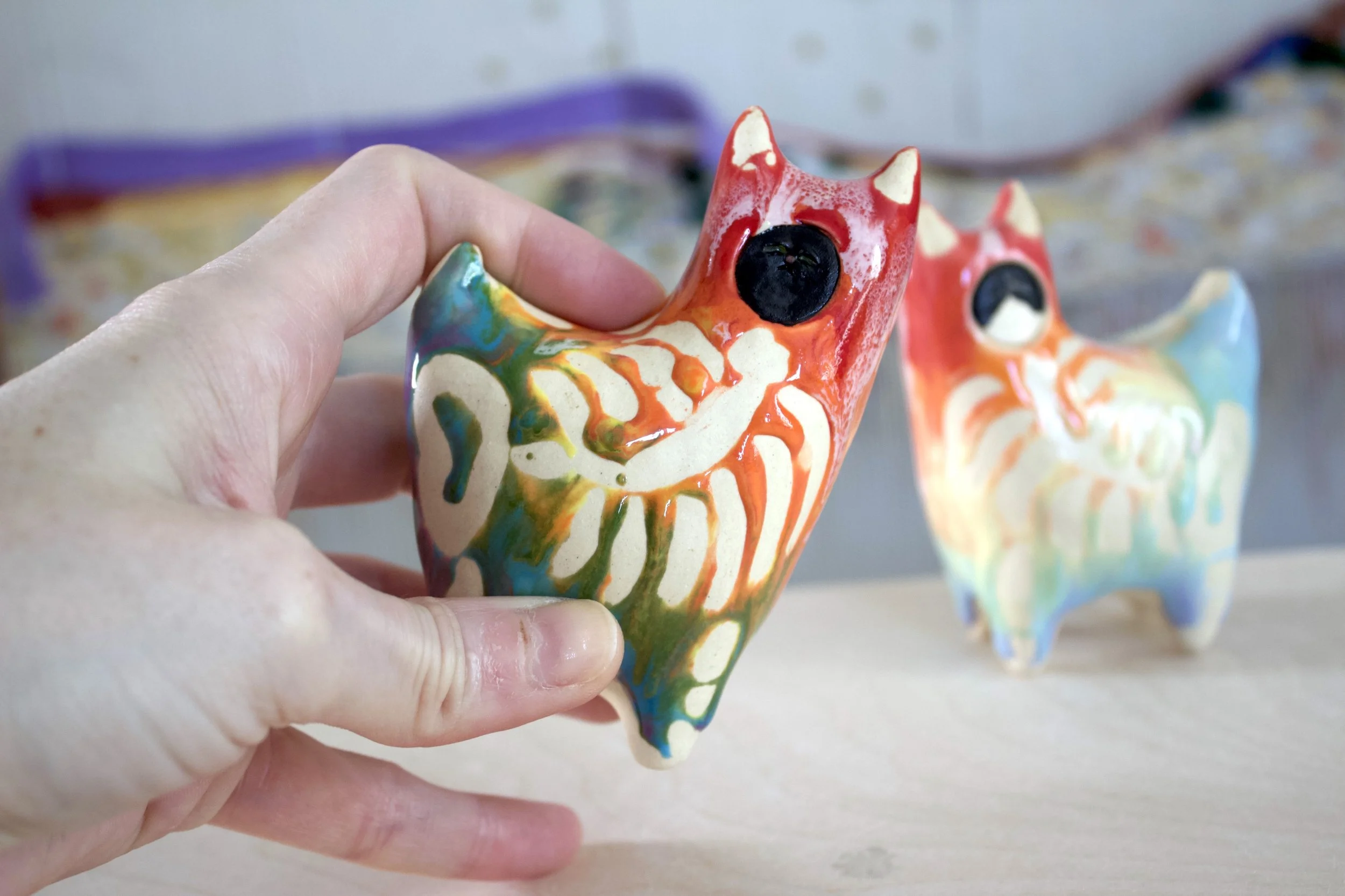 Handmade large ceramic Rainbow Goo Skeleton Black Cat shown in hand to demonstrate size and scale.jpeg