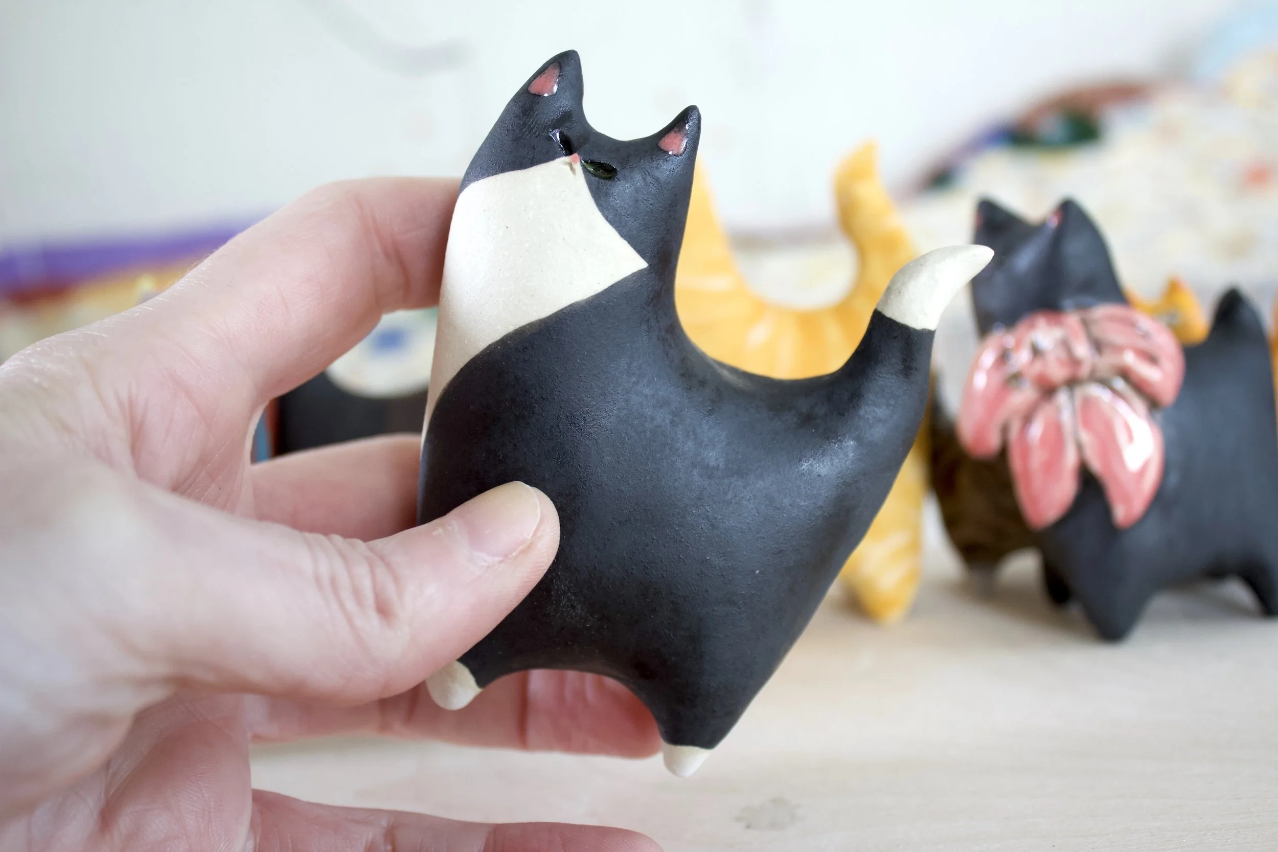 Tuxedo ceramic cat sculpture shown in hand for scale.jpeg
