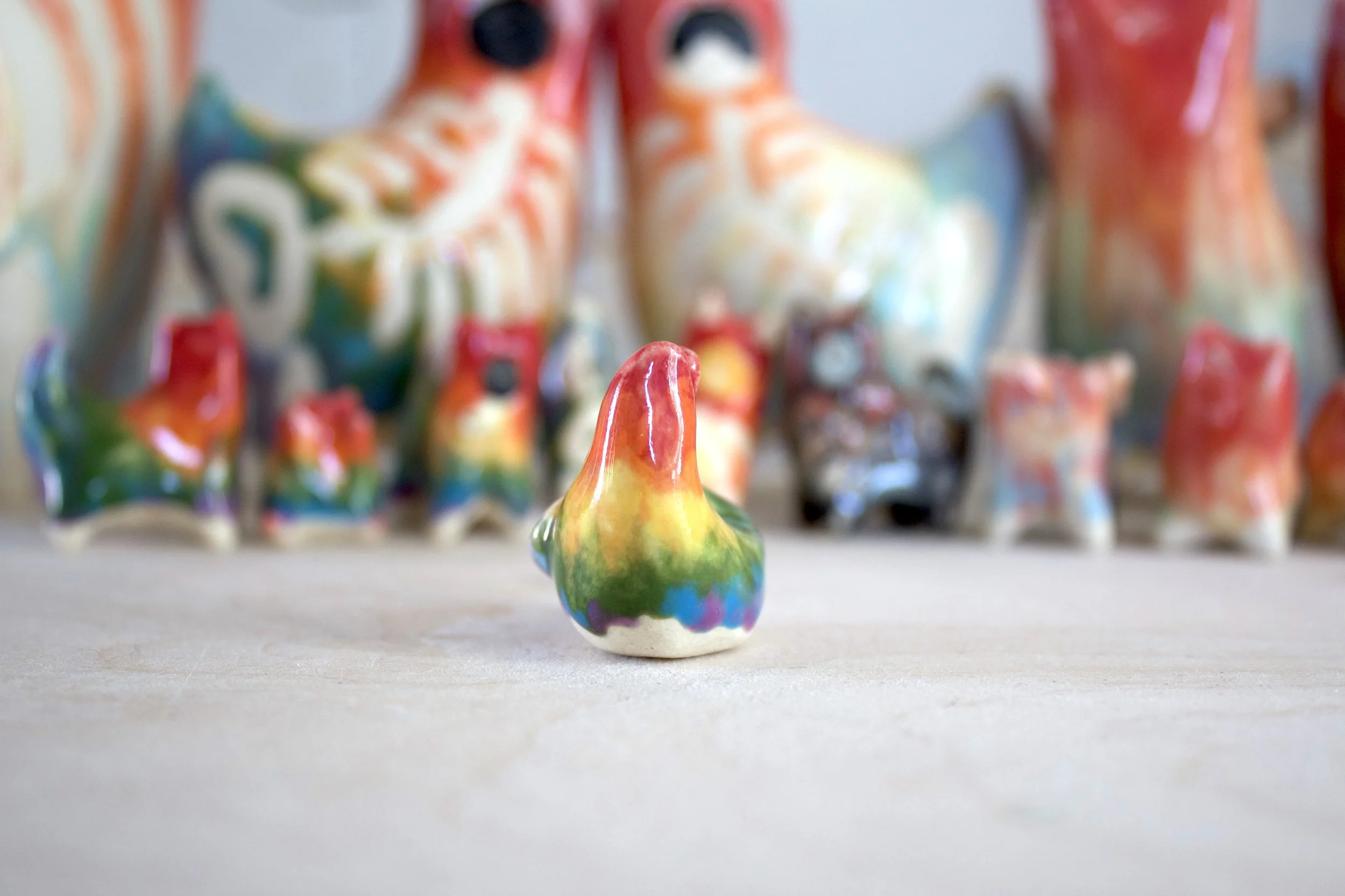 Side view of a one-of-a-kind ceramic rainbow snake cat sculpture.jpeg