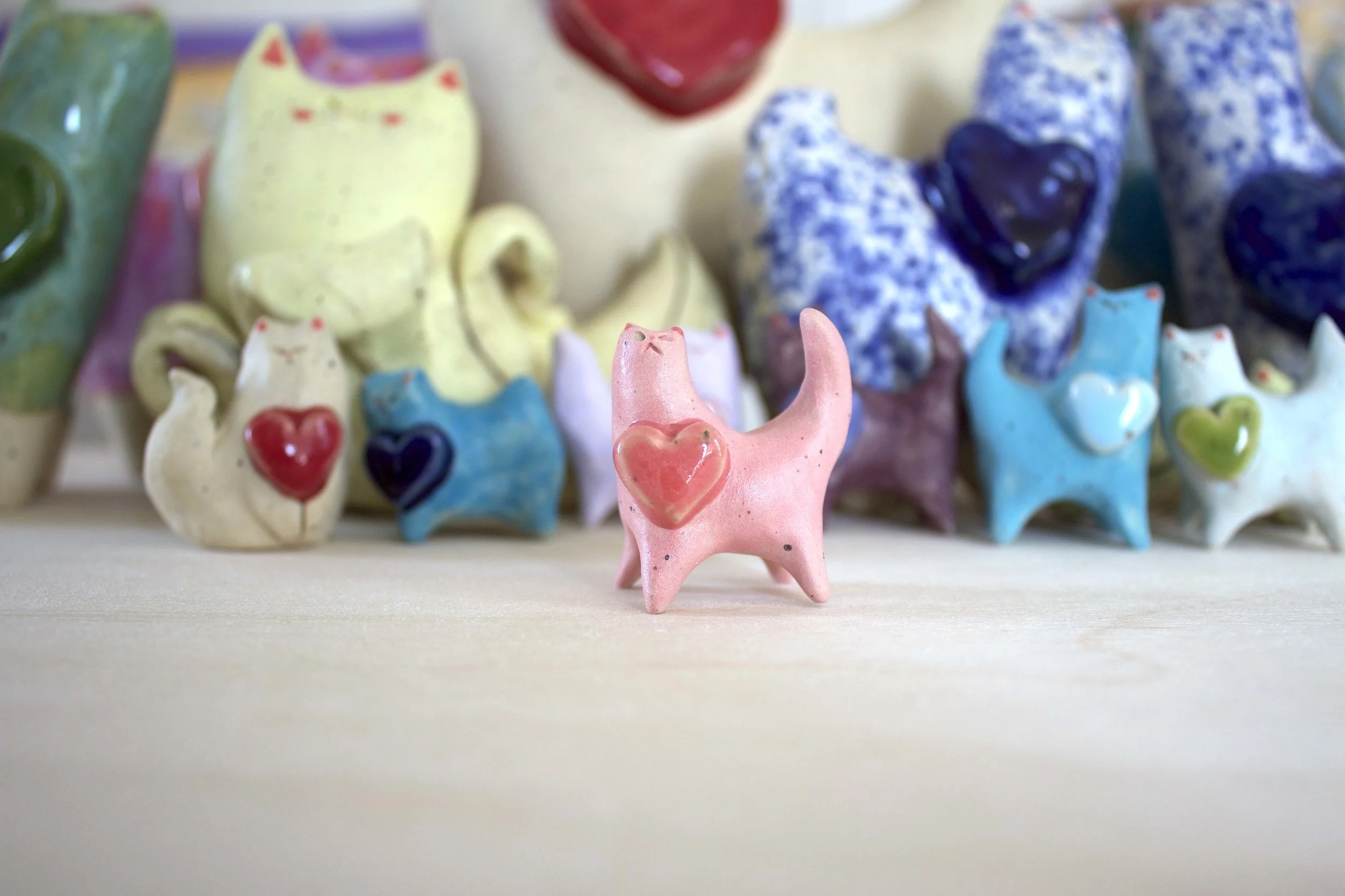 Front view of a handmade pink ceramic cat sculpture.jpeg