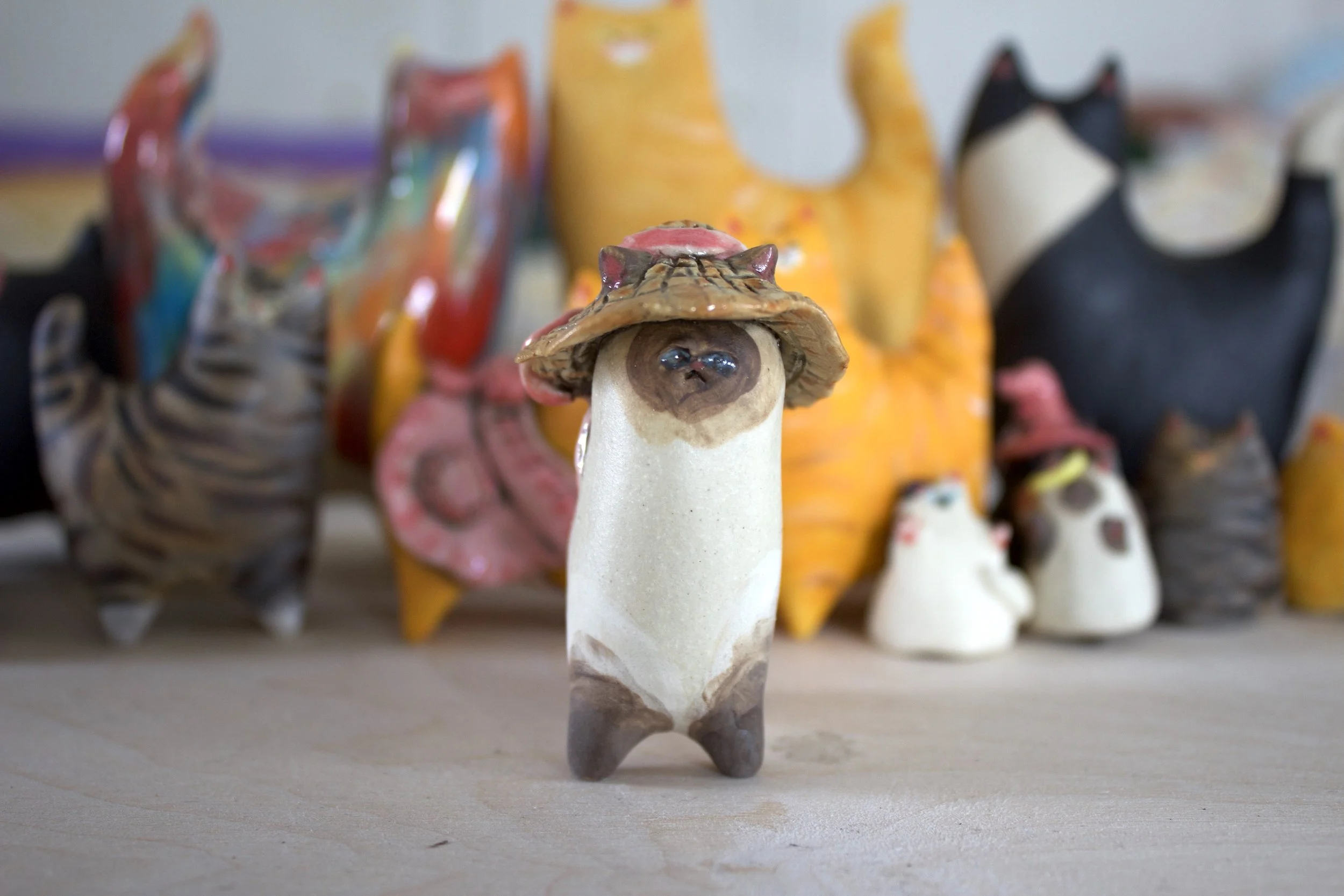 Front view Chocolate Point Siamese handmade ceramic cat sculpture with summer hat and pink bow.jpeg