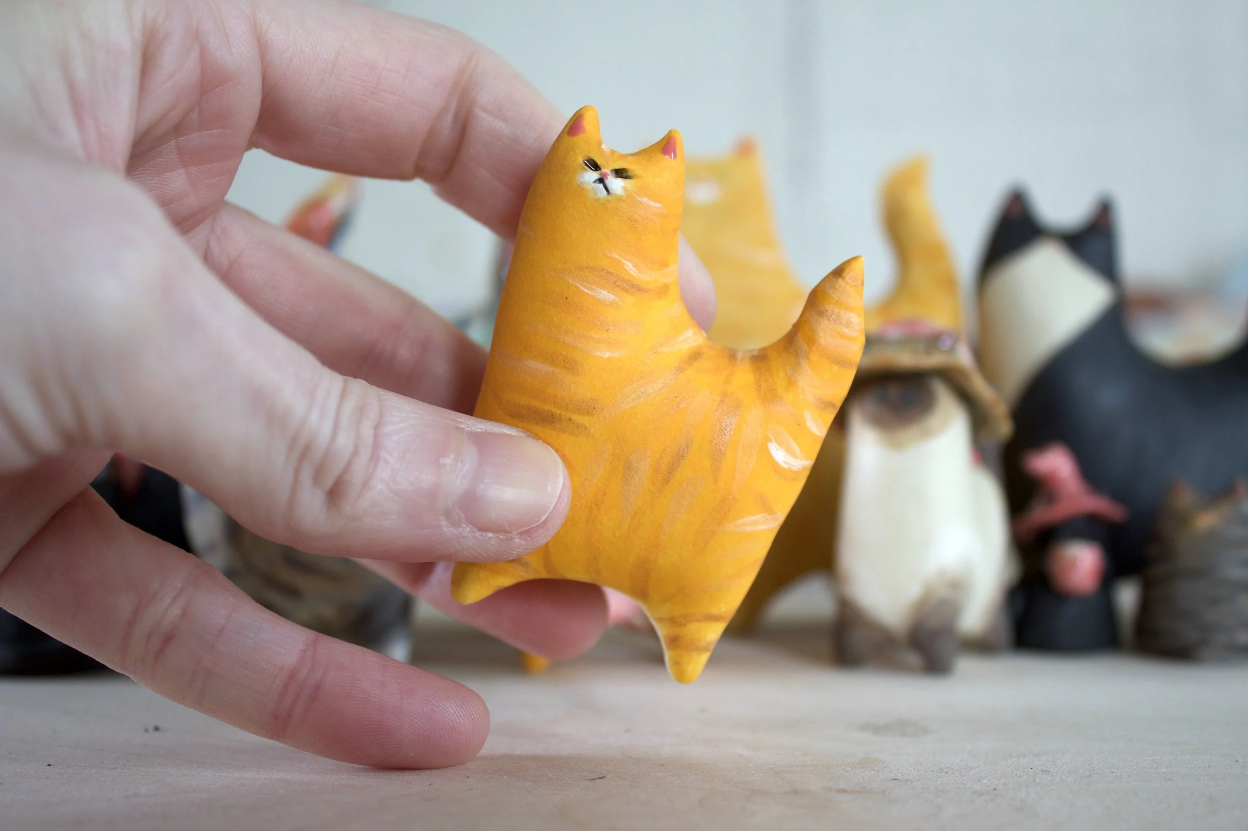 Orange tabby ceramic cat sculpture shown in hand for scale.jpeg
