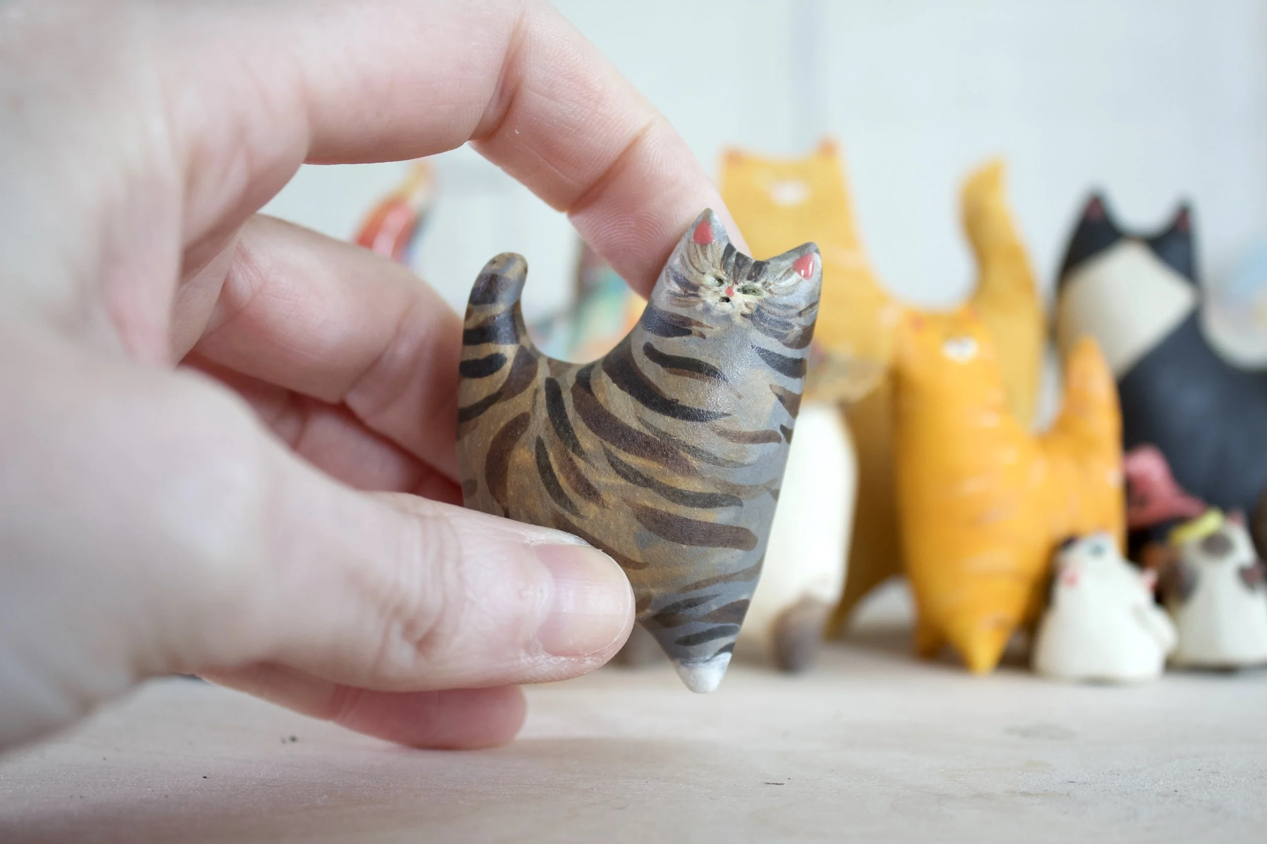 Standard Issue Tabby ceramic cat sculpture shown in hand for scale.jpeg