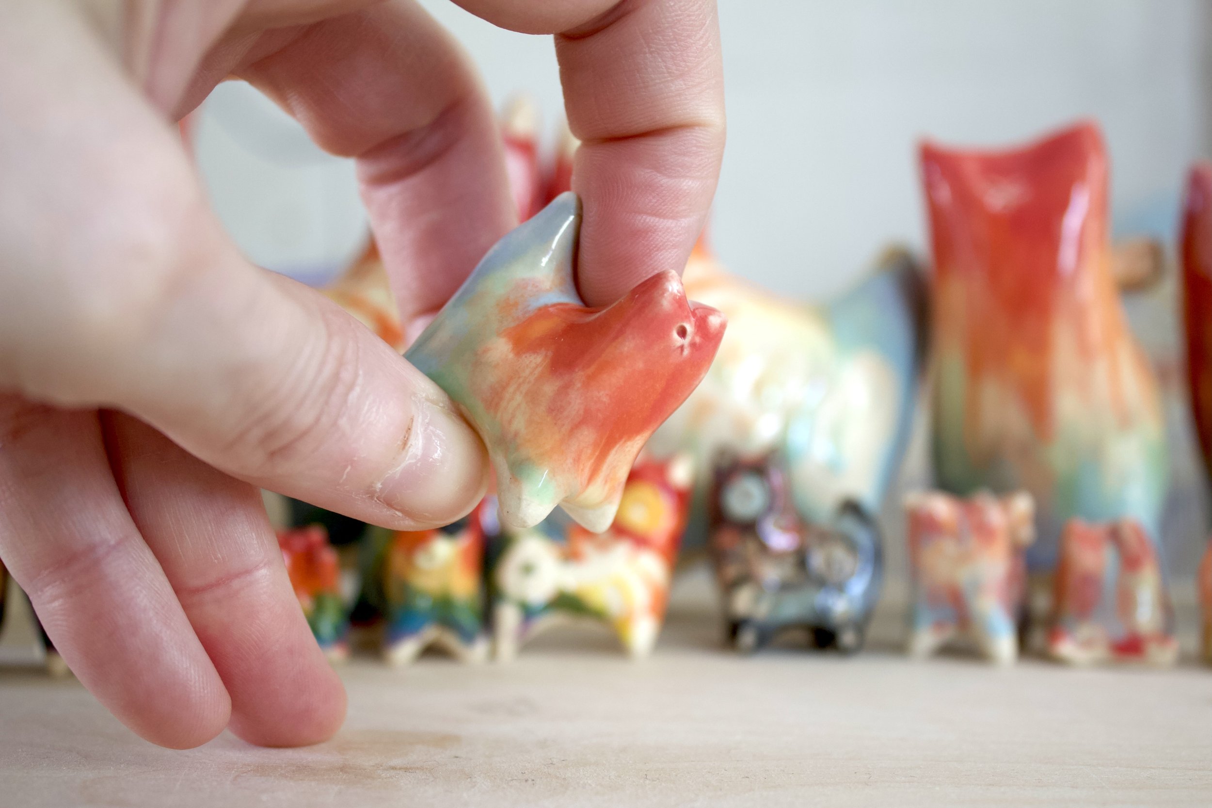 Handmade ceramic Pastel Rainbow Cat No. 2 shown in hand to demonstrate size and scale.jpeg