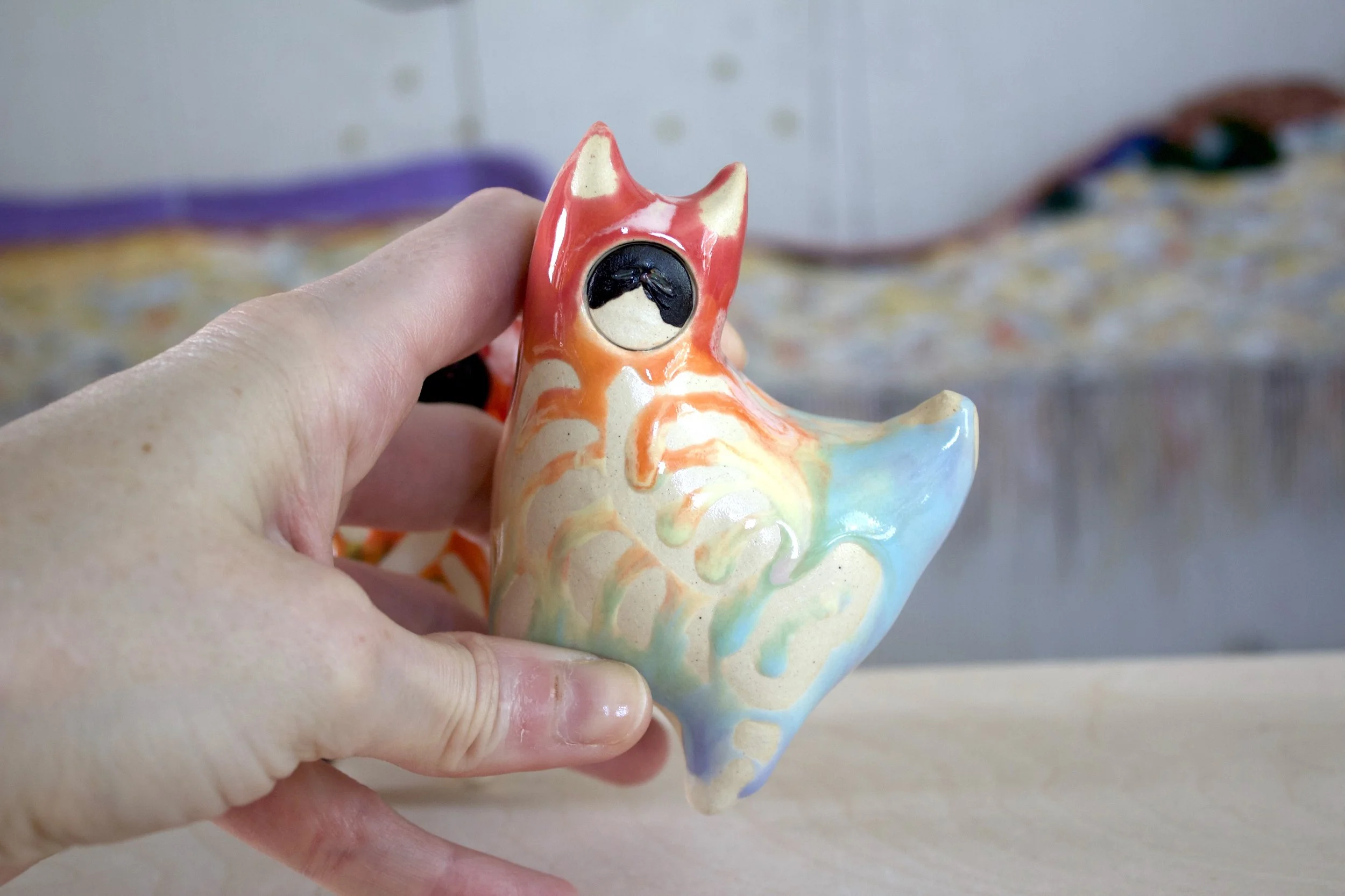 Handmade large ceramic Pastel Rainbow Goo Skeleton Cat shown in hand to demonstrate size and scale.jpeg