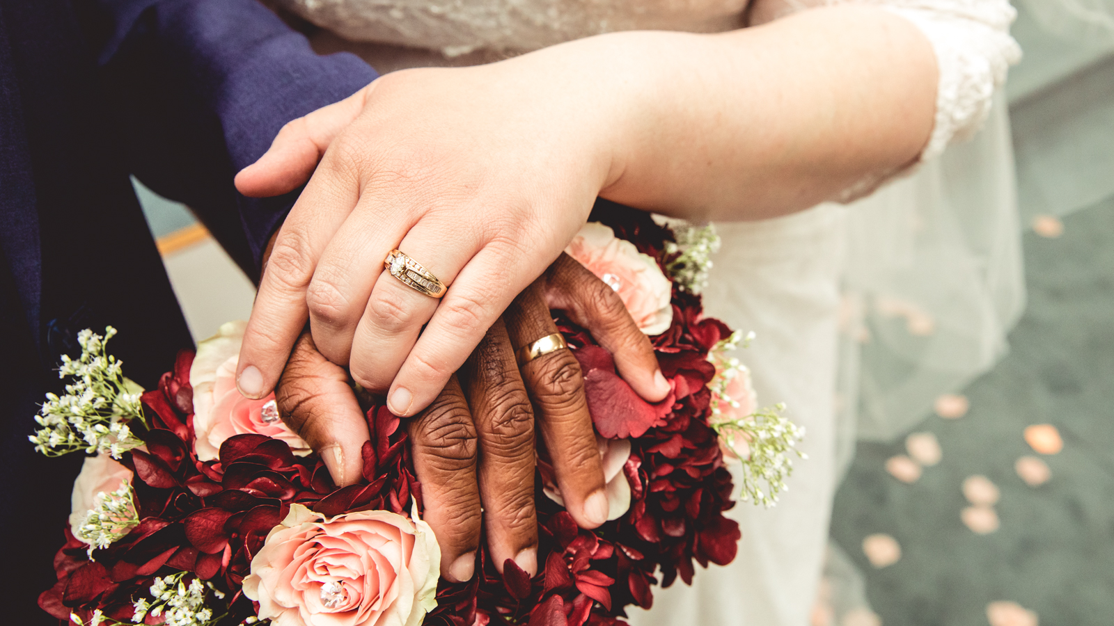 Newlywed couple clasps hands on top of bouquet
