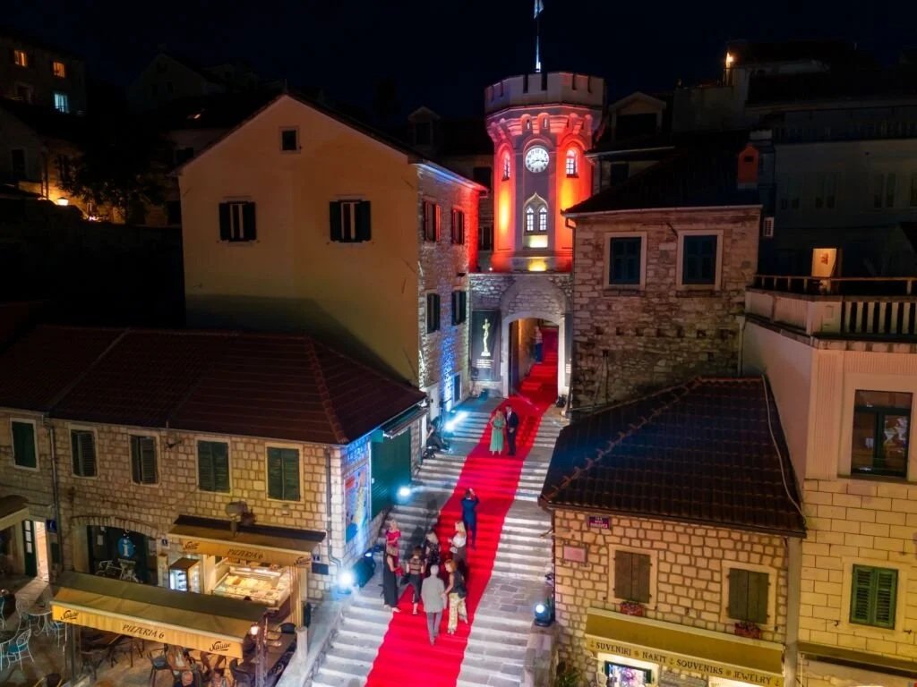 Red carpet event under the Clock Tower in Herceg Novi during a film festival.