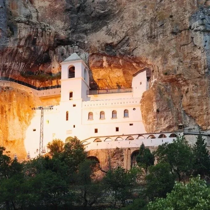 Ostrog Monastery built into the rocky cliffs of Montenegro, surrounded by mountain scenery.