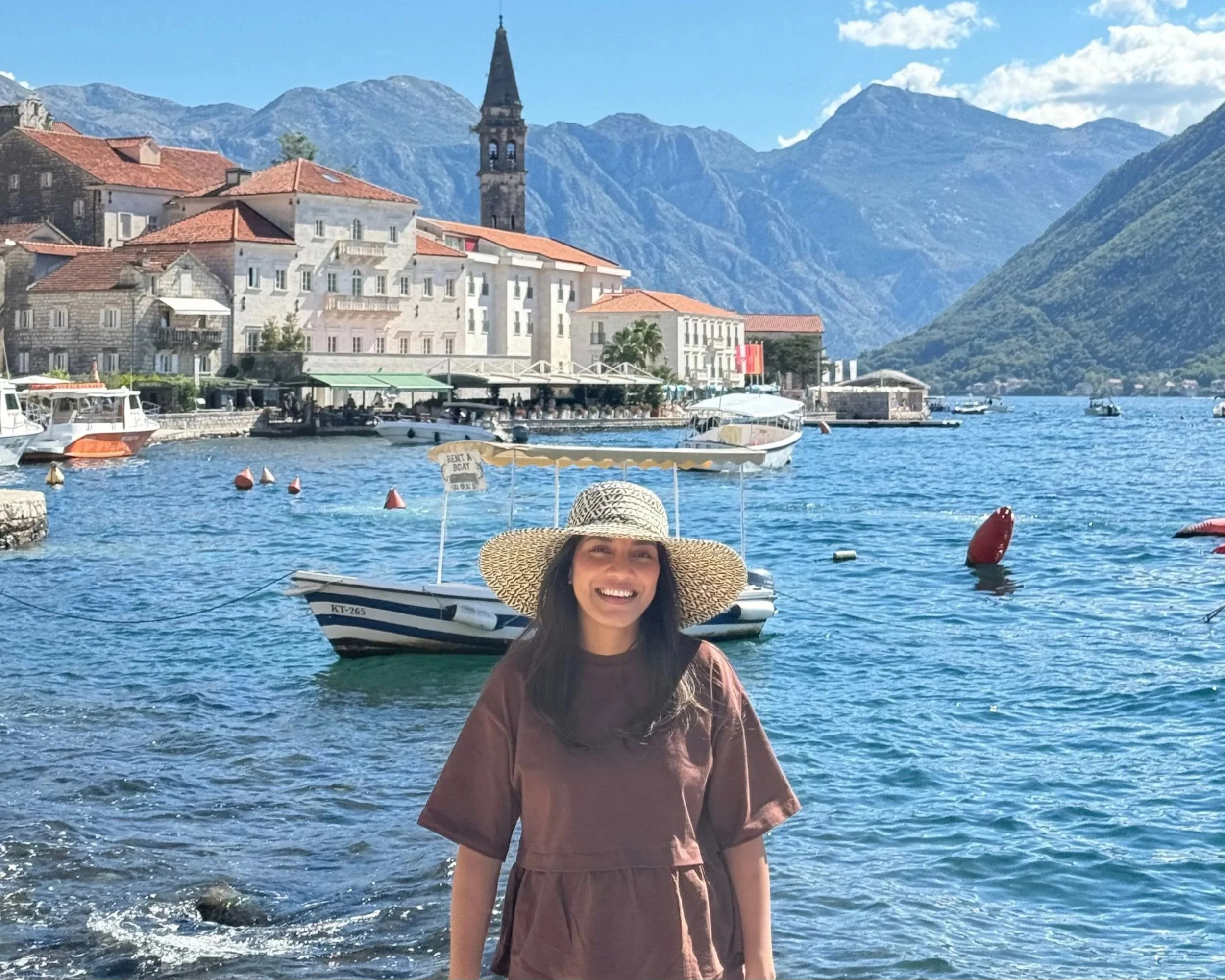 Woman posing with Perast and the Bay of Kotor in the background.