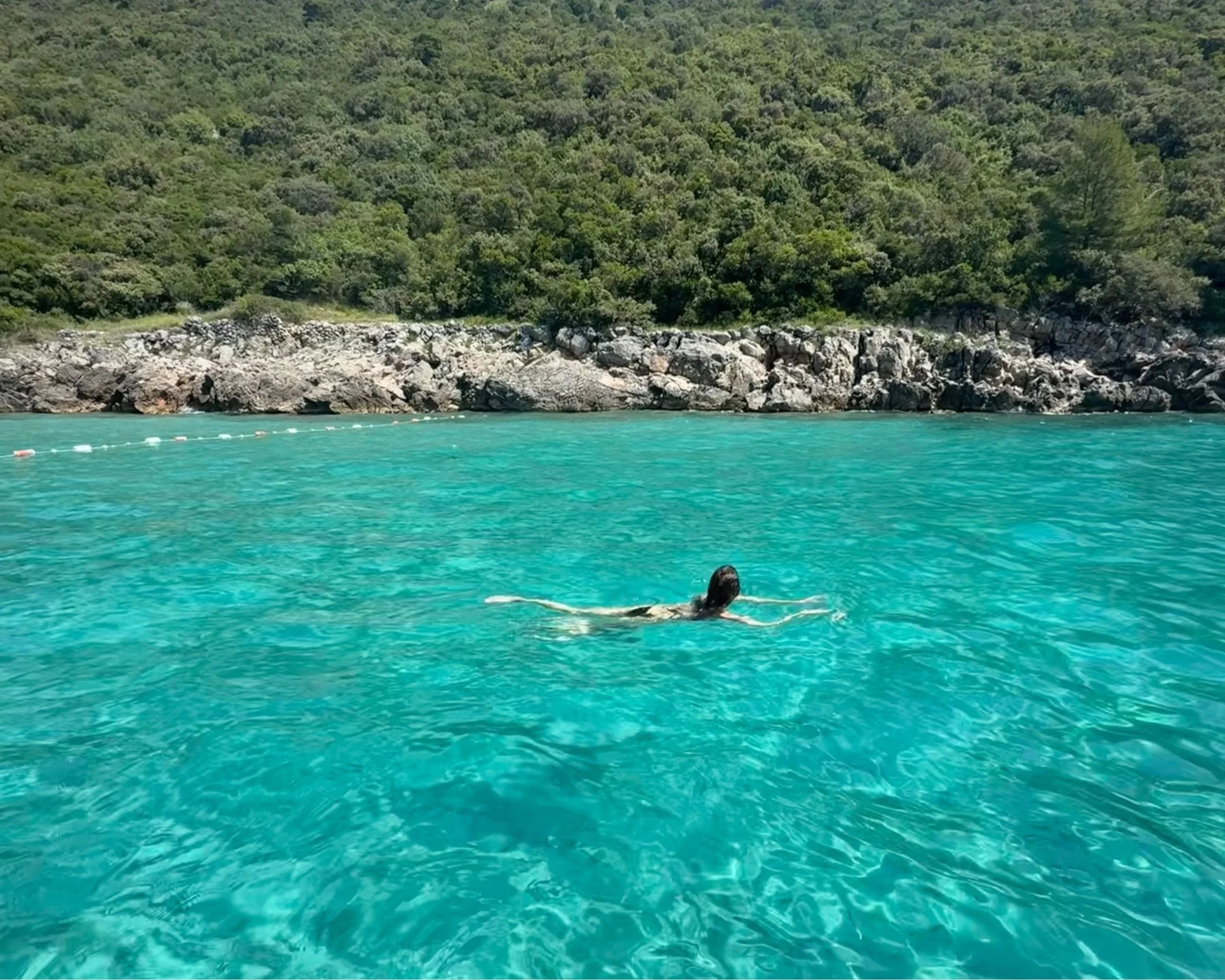 Woman swimming in the clear blue sea along the Montenegrin coast.