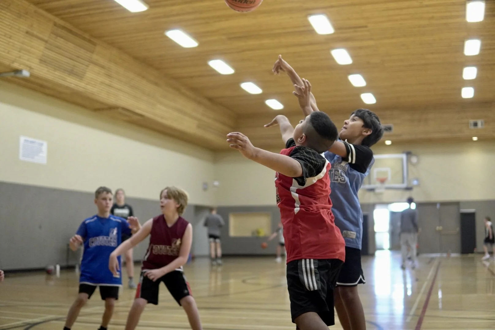 Children playing basketball in an indoor gymnasium.