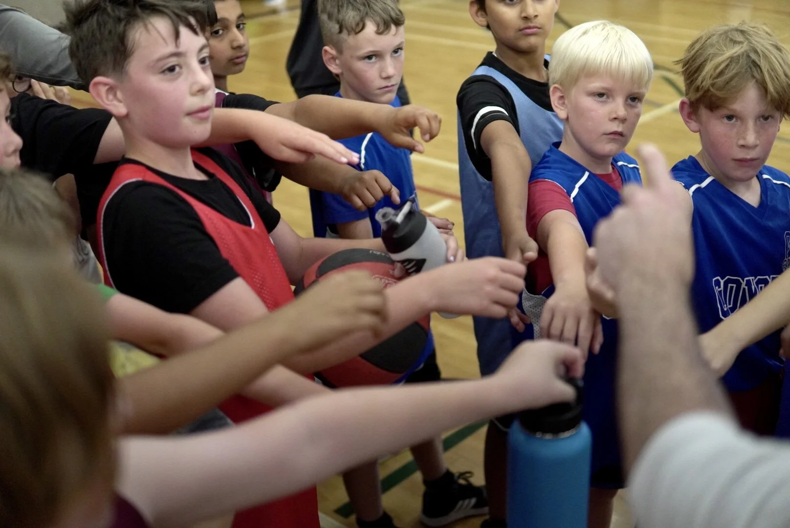 Young boys in sportswear standing in a gymnasium, listening to their coach during a sports practice or game.