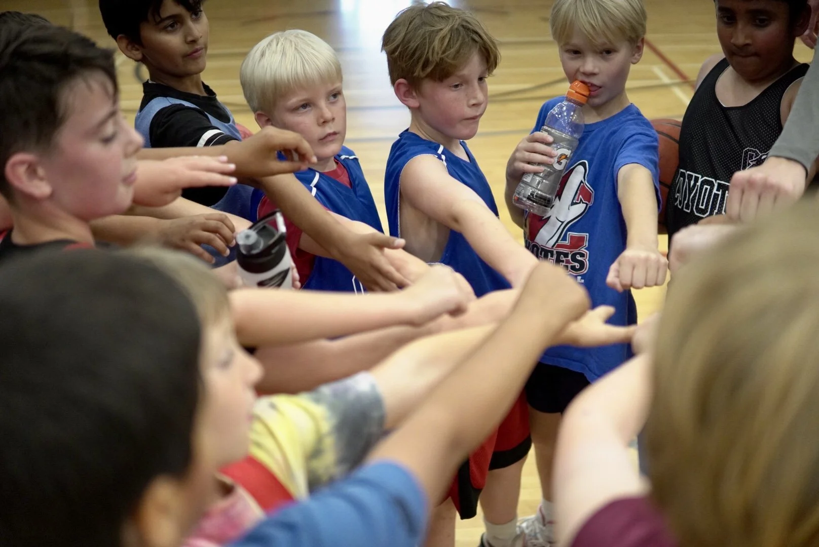 Group of young children in sports uniforms gathering in a gym, showing teamwork and determination.