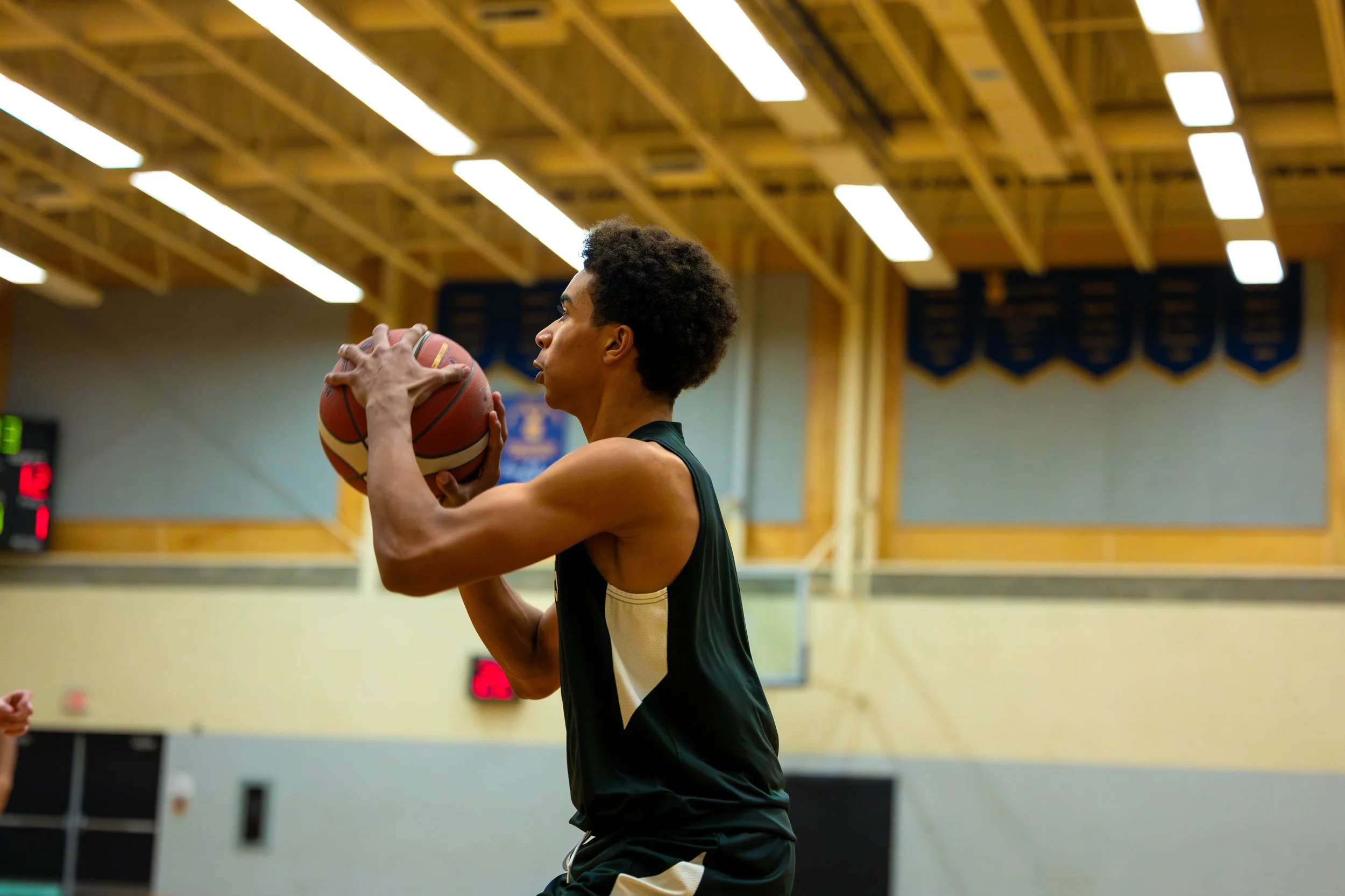 A young male basketball player preparing to shoot a free throw in a gymnasium.