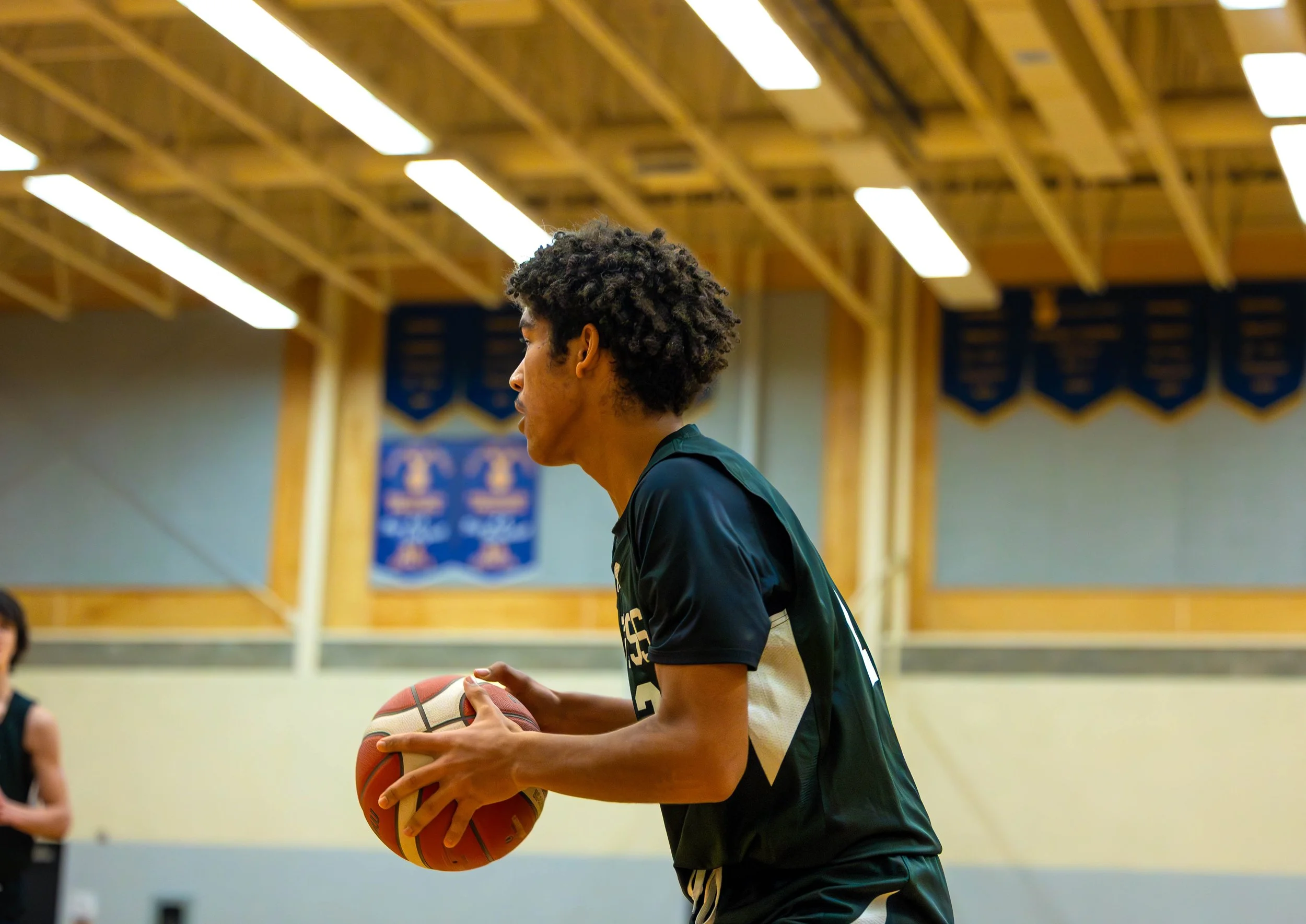 Young basketball player holding a basketball in a gymnasium.