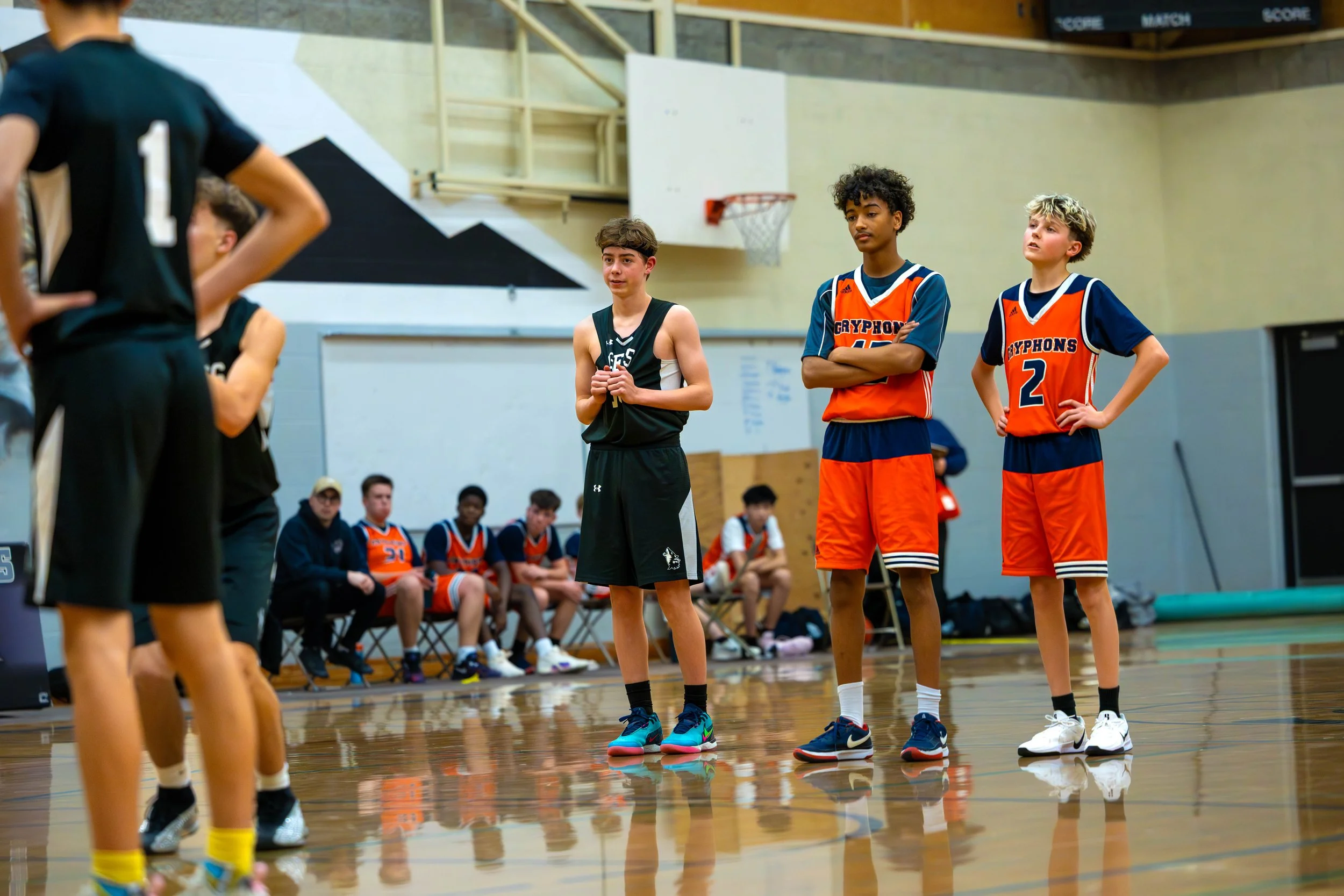 Young basketball players in uniform standing on a gymnasium court during a game or practice.