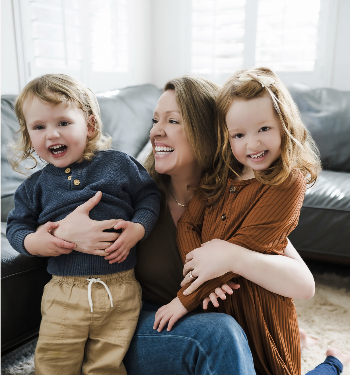 Smiling family of three outdoors, holding a child.