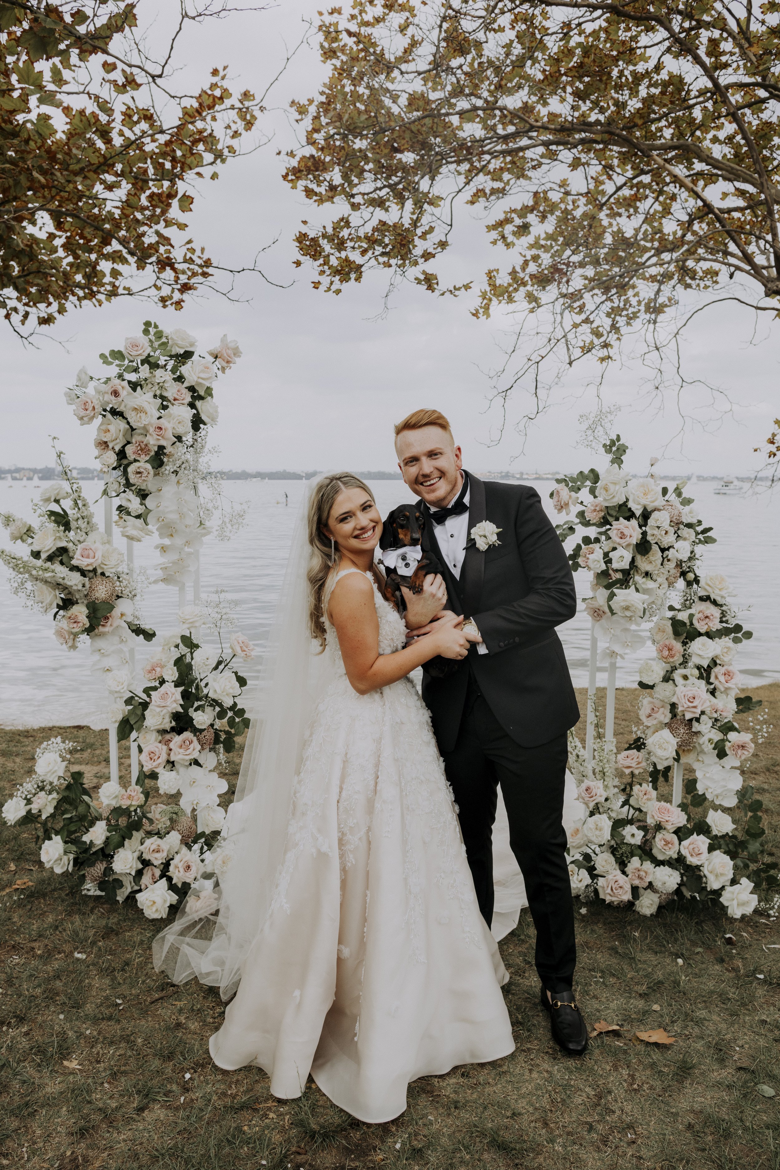 Bride and groom beside white and blush floral ceremony installation at Lamont's Bishops House in Perth