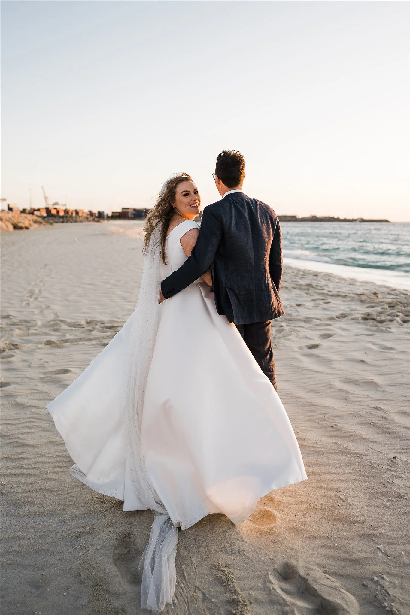 Bride and groom walking along the beach at Coast Port Beach in Fremantle