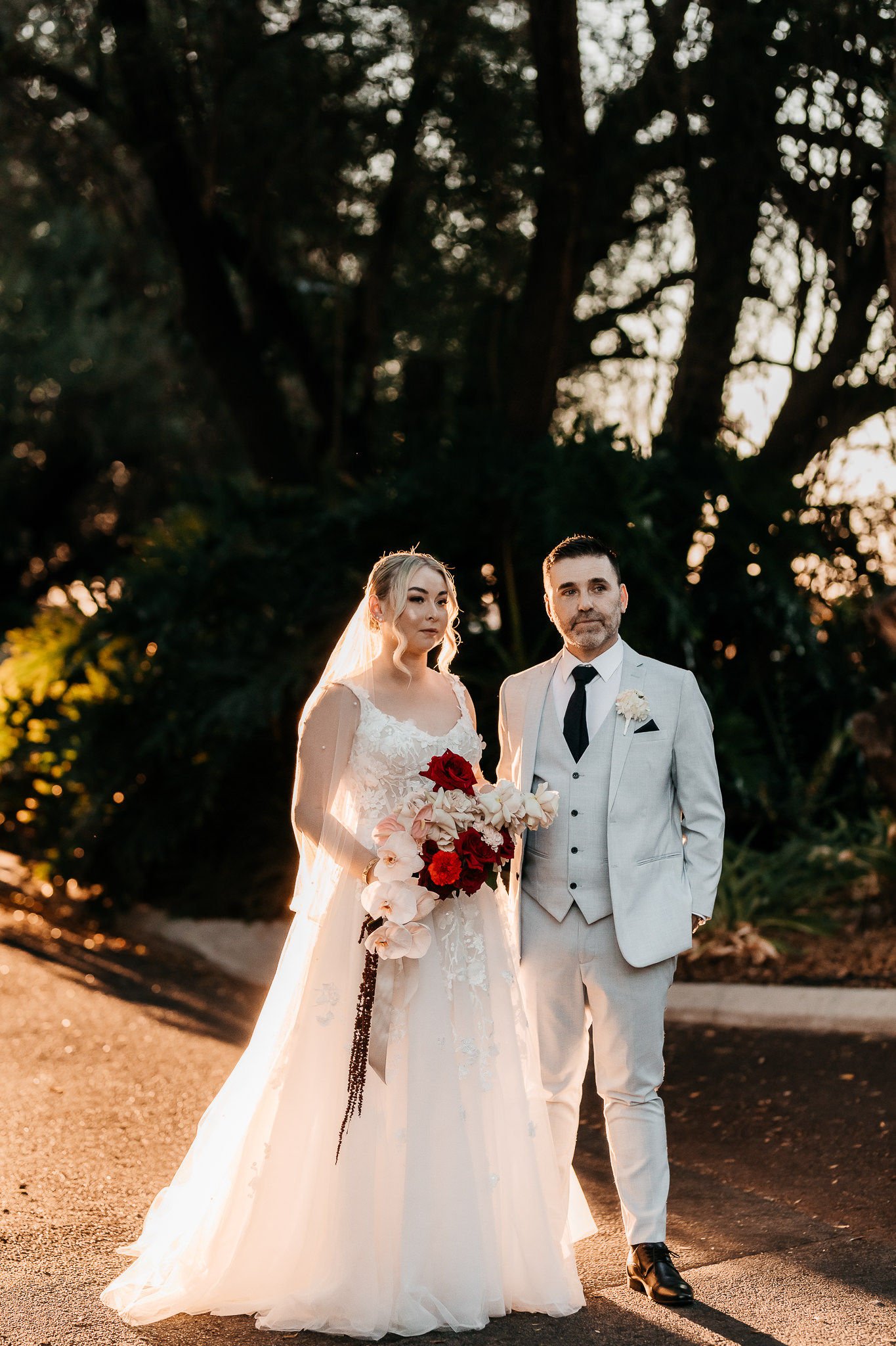 Bride and groom with red and pink wedding flowers at Caversham House in Perth