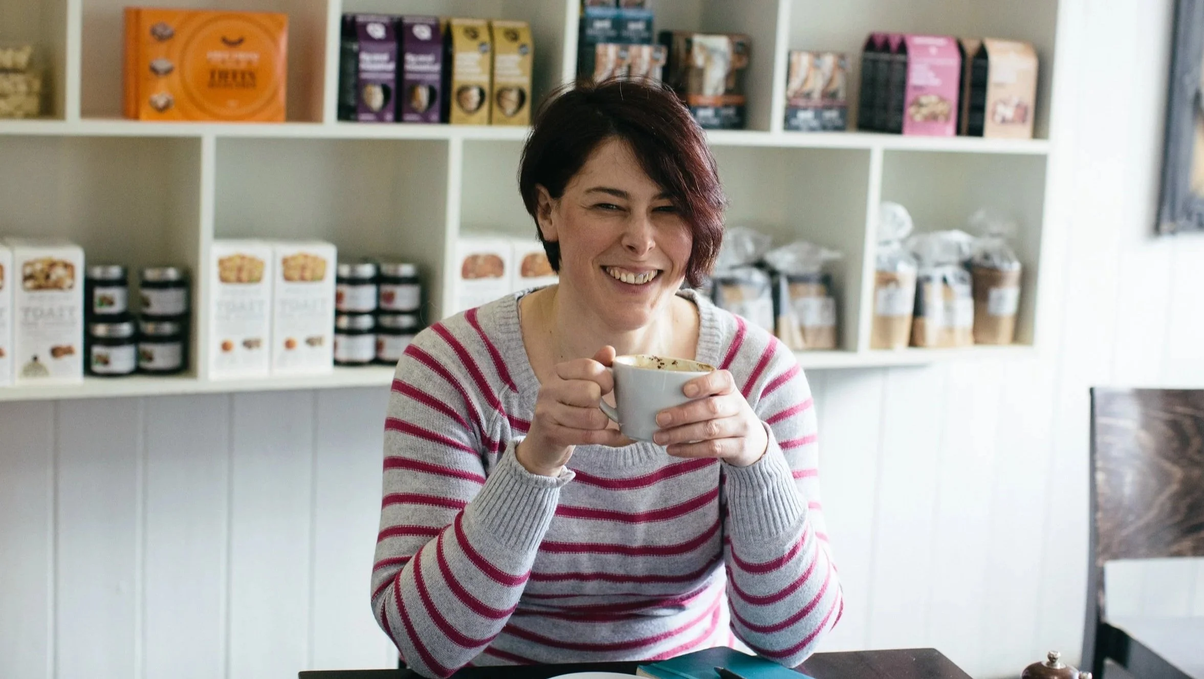 Anna holding a cup of coffee and laughing