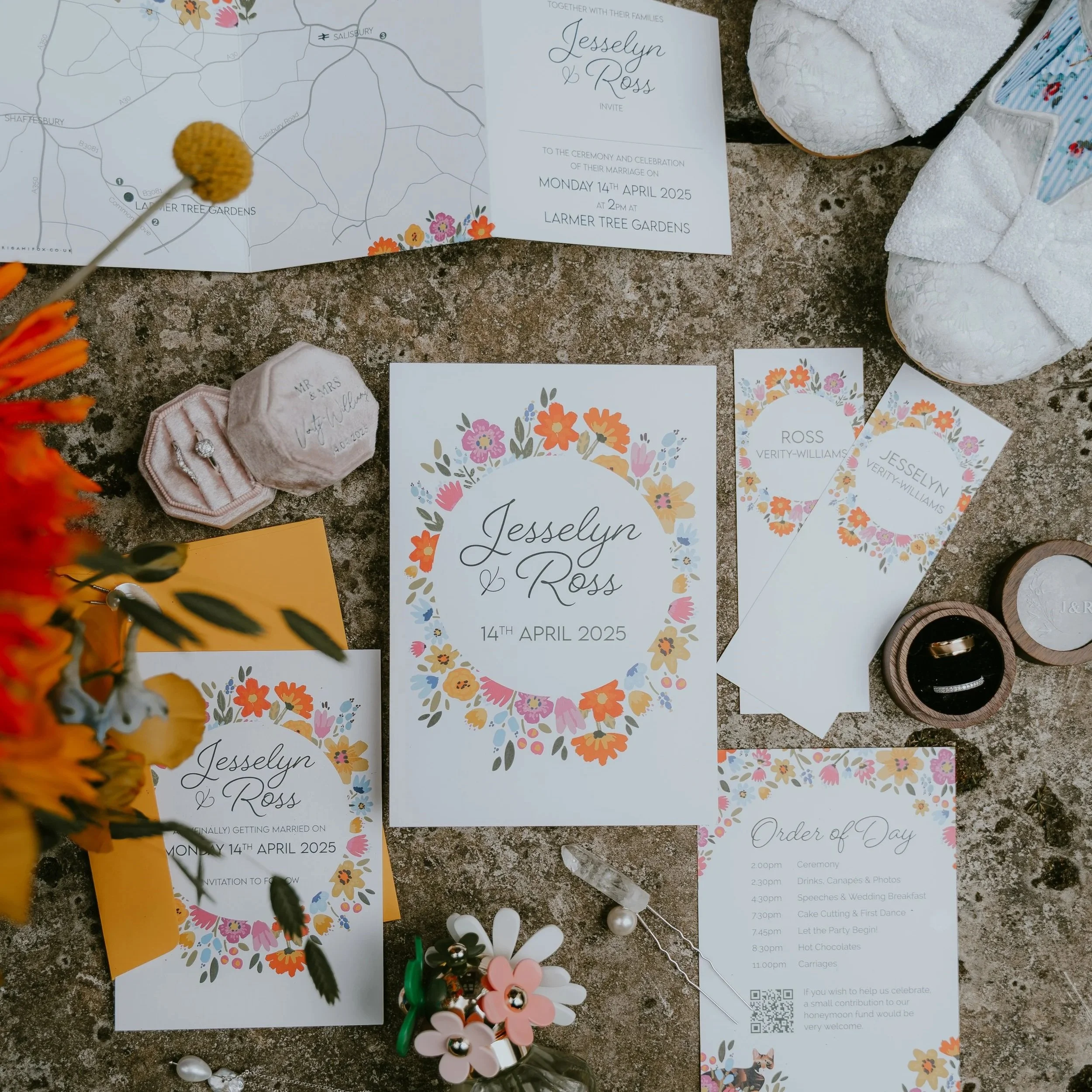 A flatlay of a bright flower filled wedding stationery suite