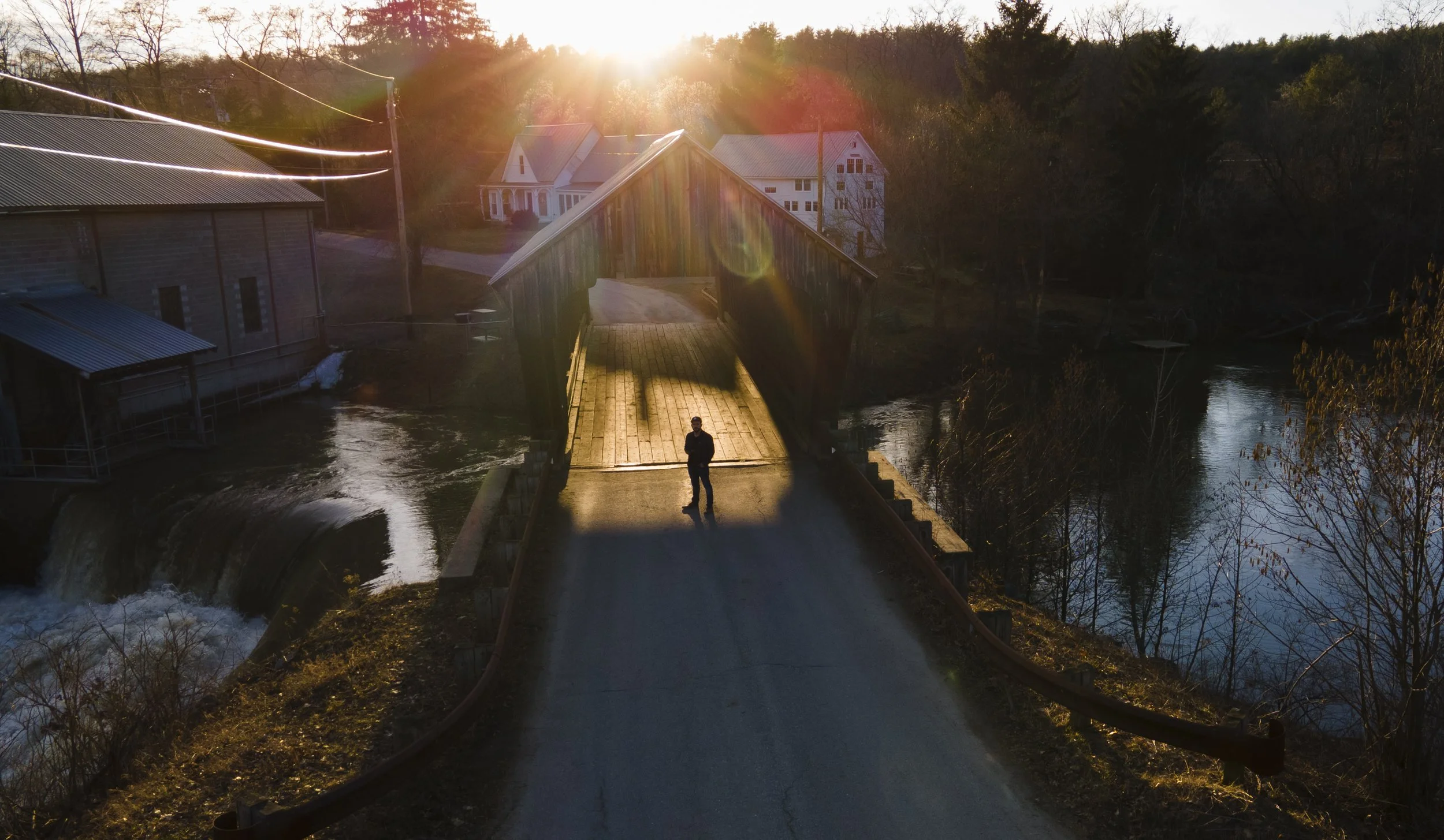 A self portrait of a drone operator in front of a covered bridge at sunset.