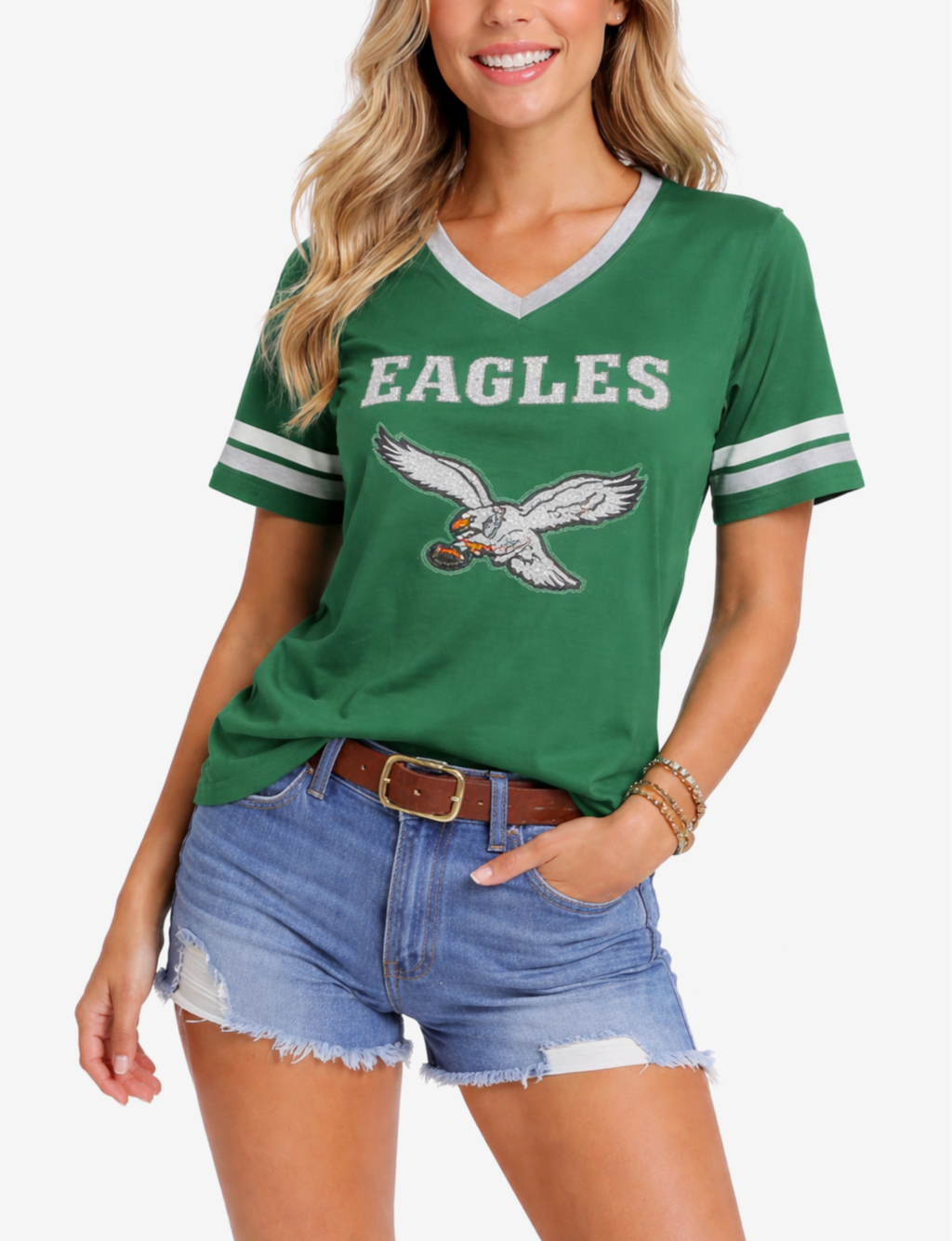 A woman wearing a green Eagles sports jersey and distressed denim shorts.