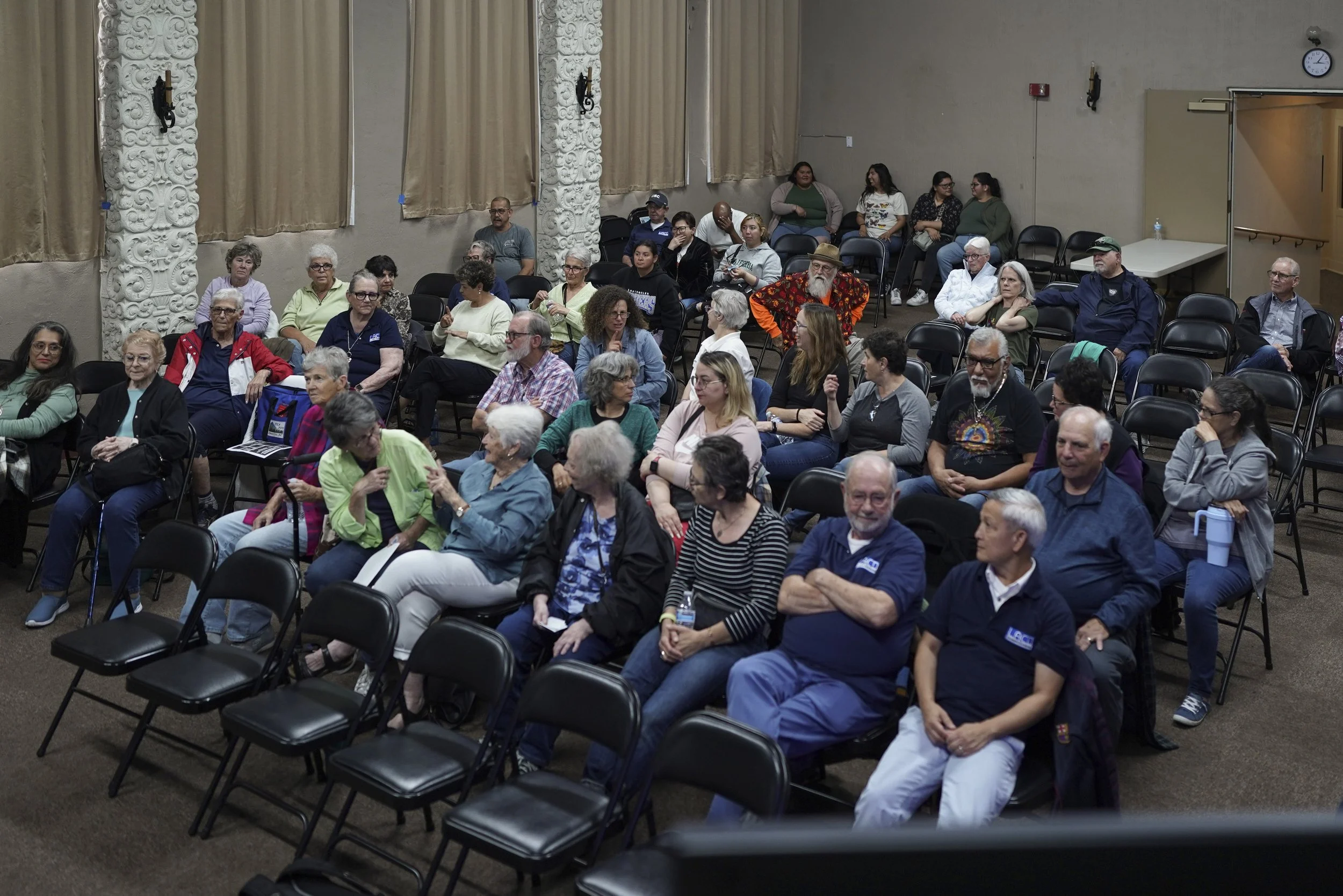 A wide view shows a diverse audience gathered in a hall for a community screening of Being Michelle.