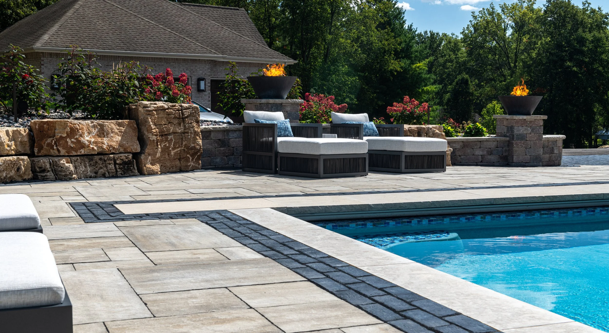 Unilock paver patio with pool, retaining wall, and fire features.jpeg