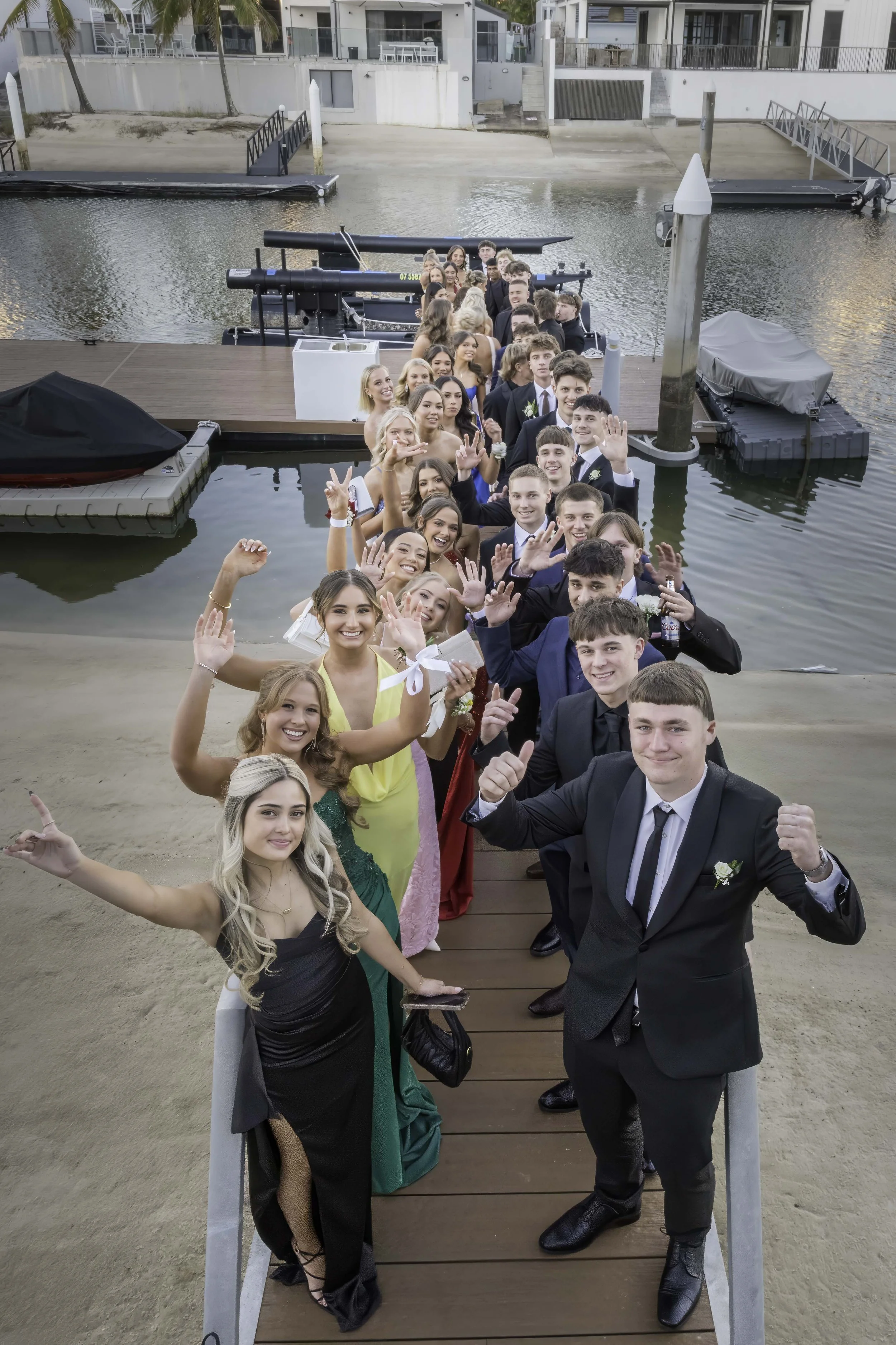 Large group of high school students in formal wear posing together on a waterfront pier for a Gold Coast formal photographer.