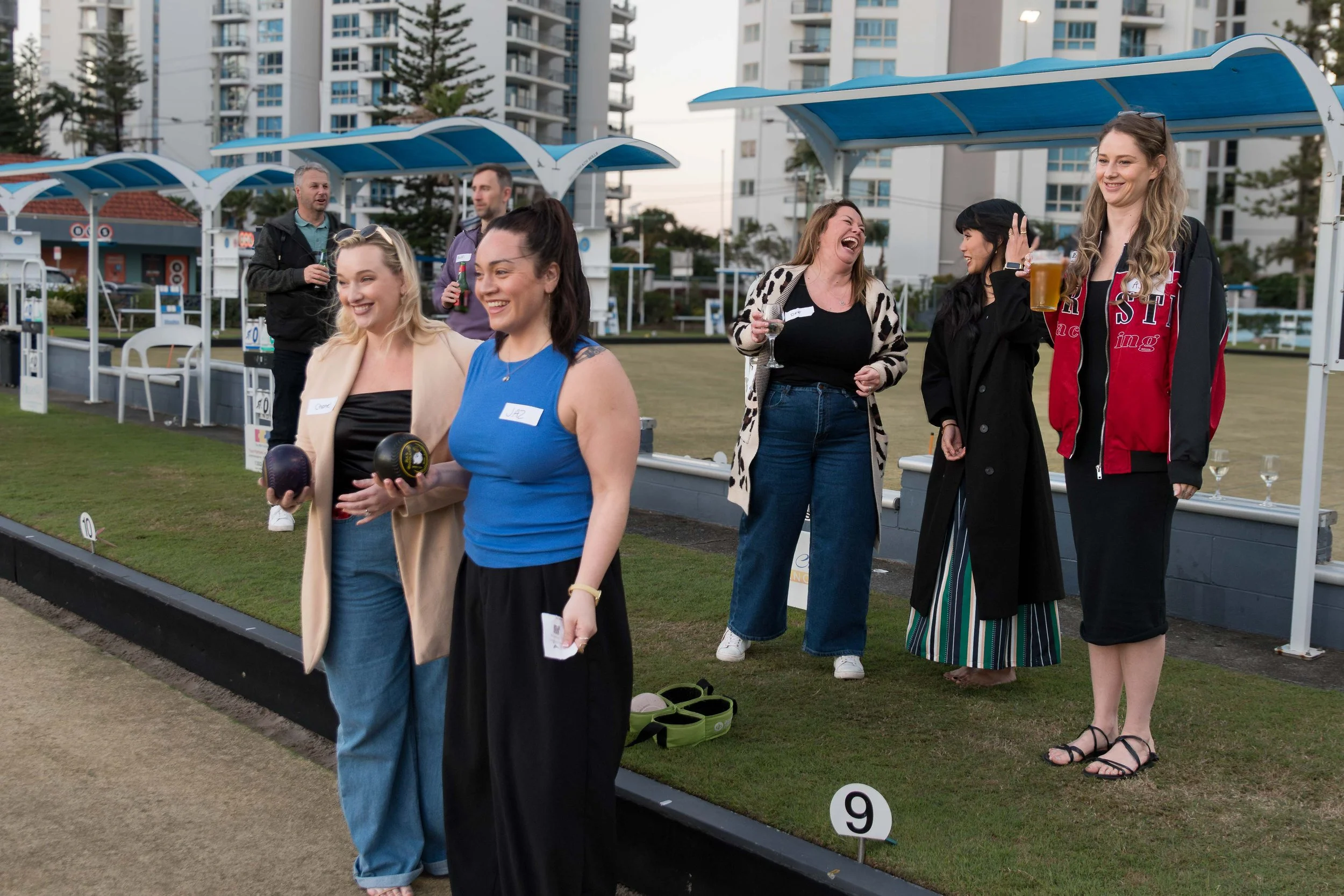 Group of professional women laughing and socializing by the green during a Hub24 corporate event at Broadbeach Bowls Club.