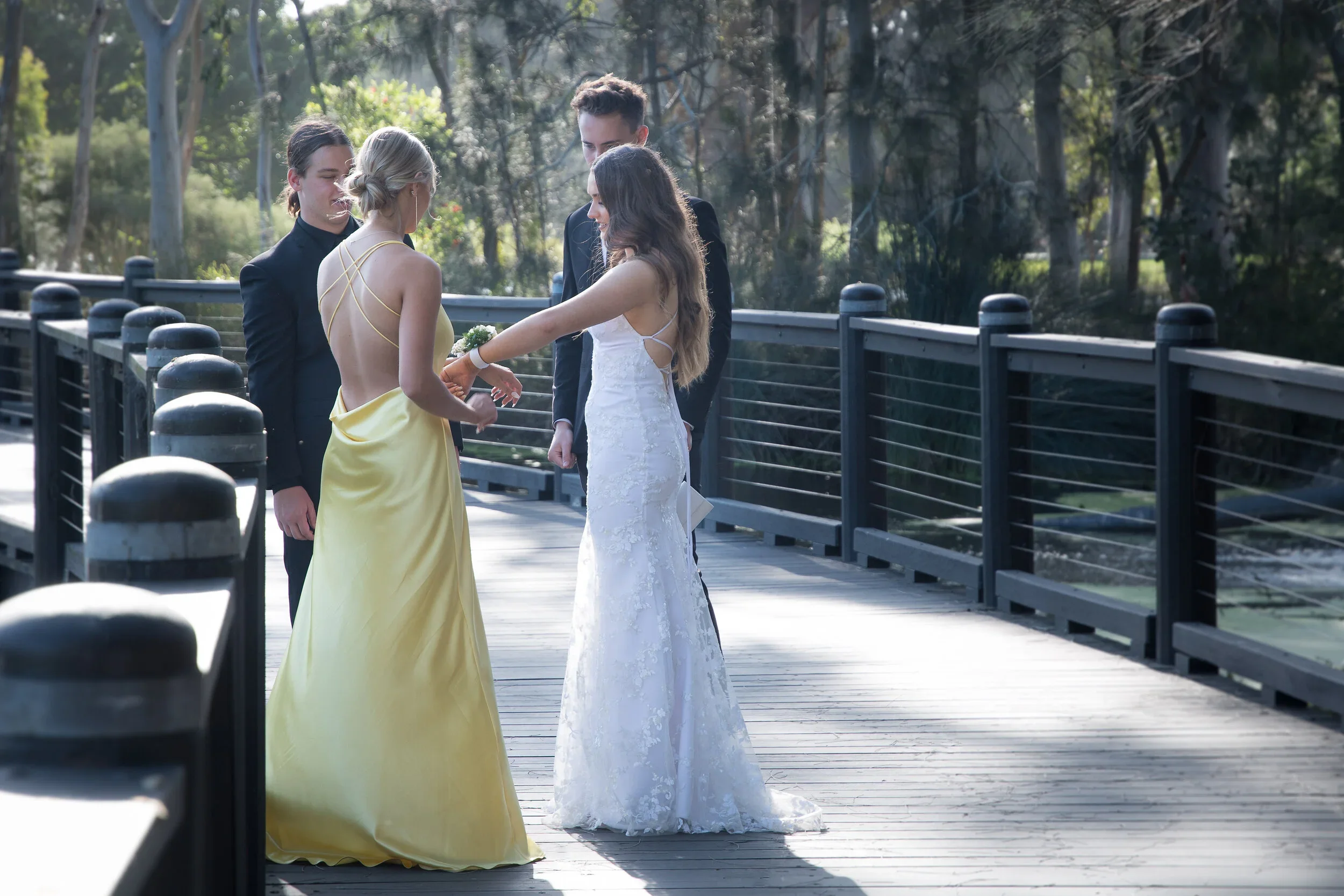 High school formal students putting on a floral corsage on the wooden boardwalk at the Gold Coast Regional Botanic Gardens in Benowa, captured by photographer Scott Hardy.