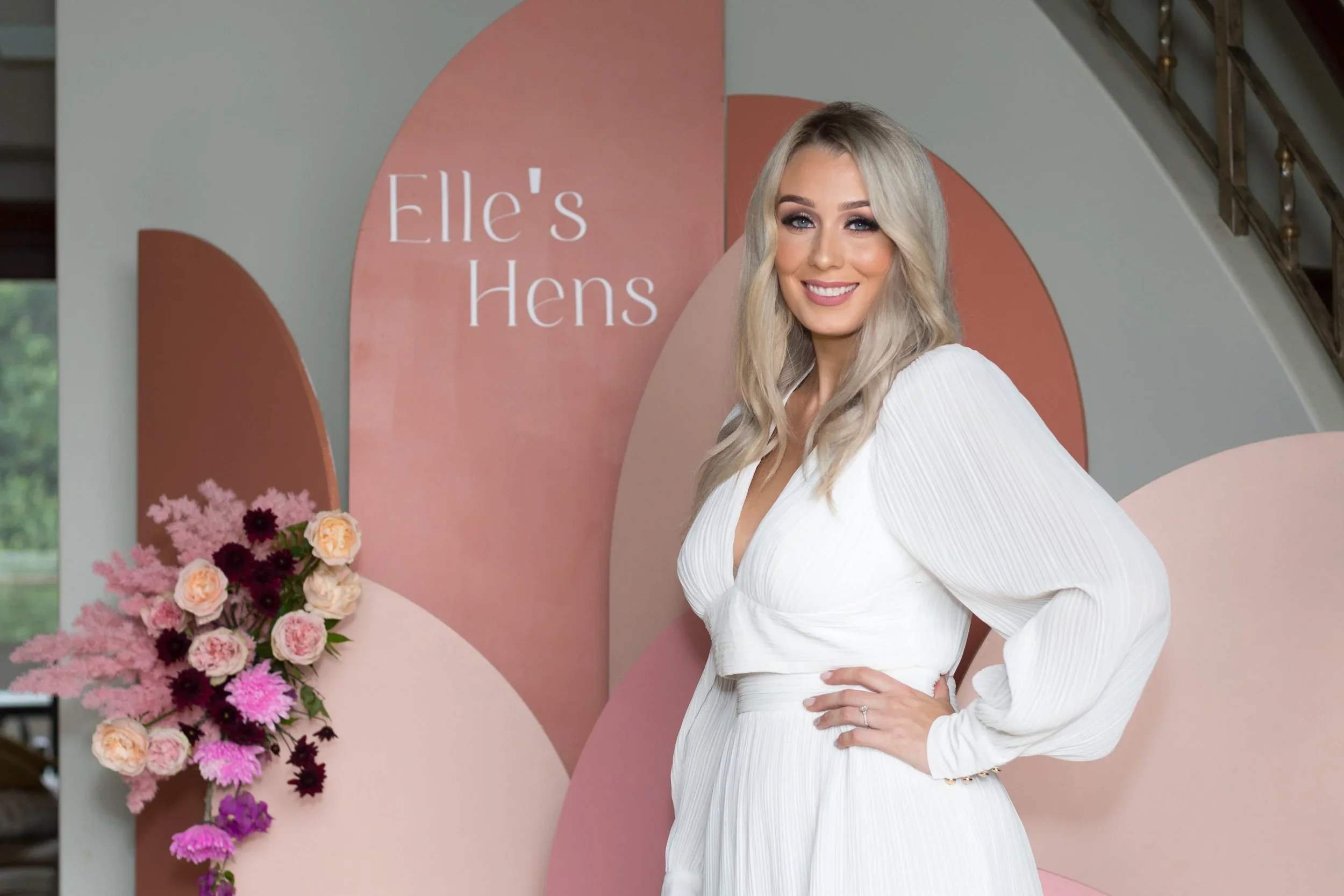 The bride-to-be standing in front of a pink floral backdrop at her hens party on the Gold Coast.