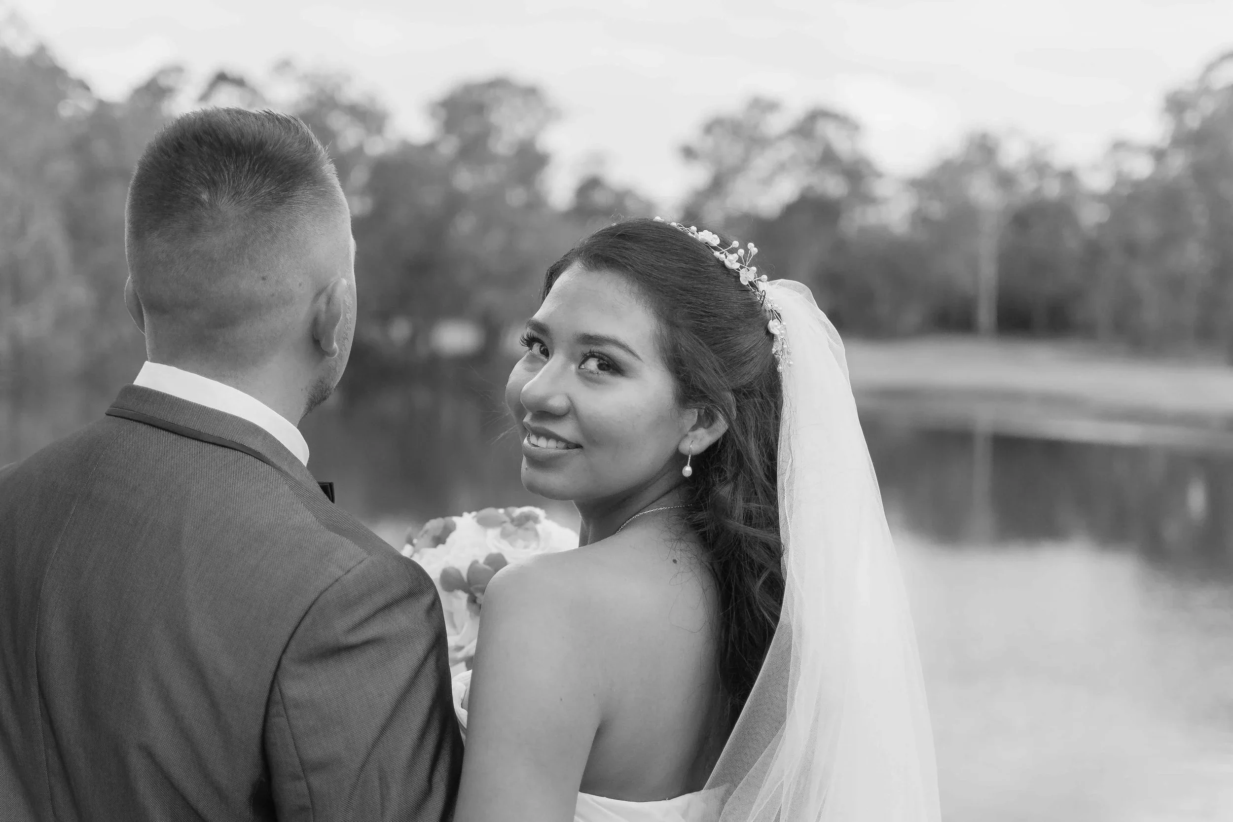 A bride looking back over her shoulder with a smile next to the groom in a black and white portrait at a Gold Coast Country Club wedding, photographed by Scott Hardy