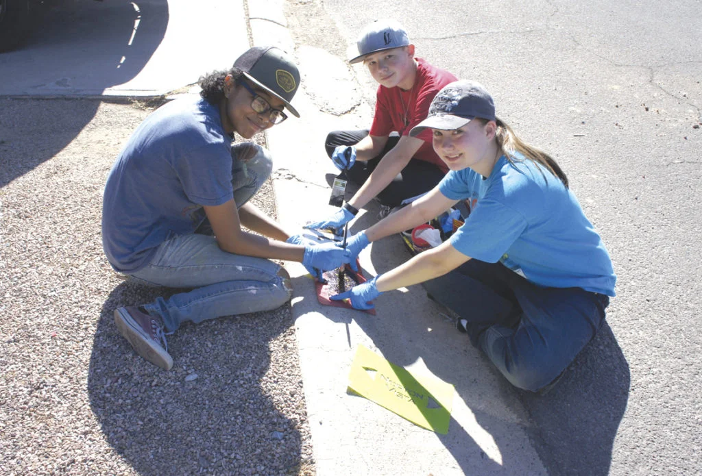 Local youth who volunteered on April 27 to paint house numbers and a sun logo on curbs in the Norton Vista neighborhood included, clockwise from left: Grace Williams, David Wiesinger and Rose Wiesinger (photo by Teri Carnicelli).